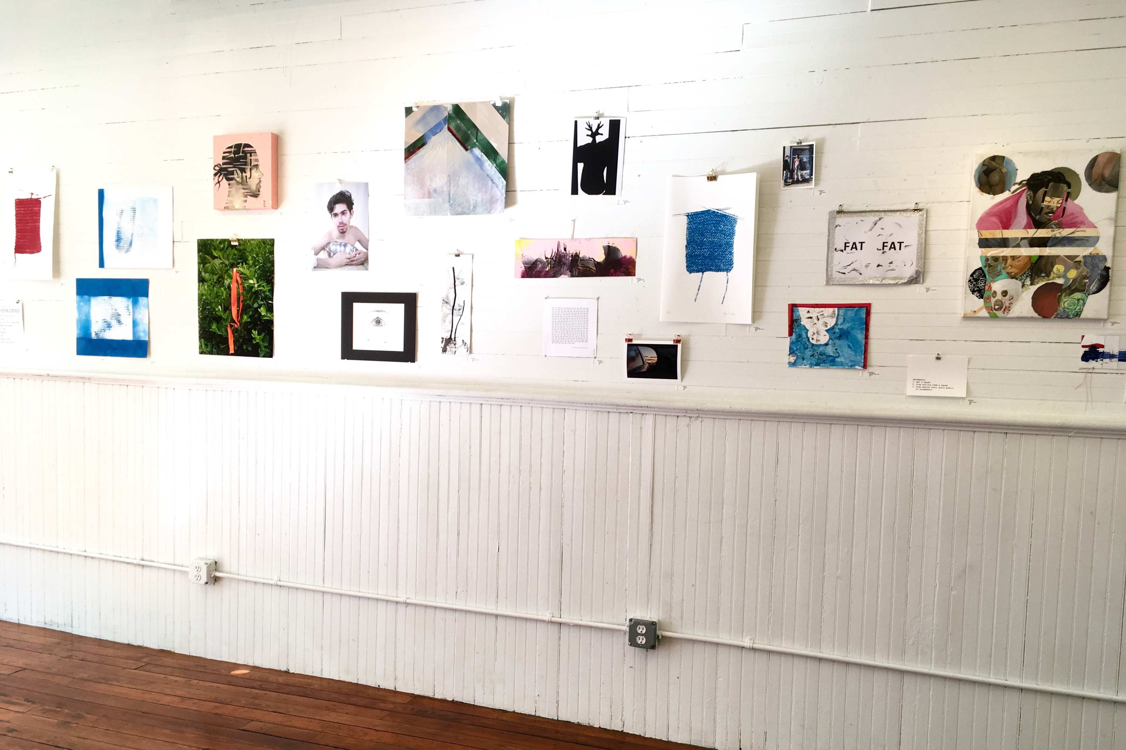 A gallery wall featuring a diverse array of framed artworks and photographs arranged in a grid on a white wooden background.
