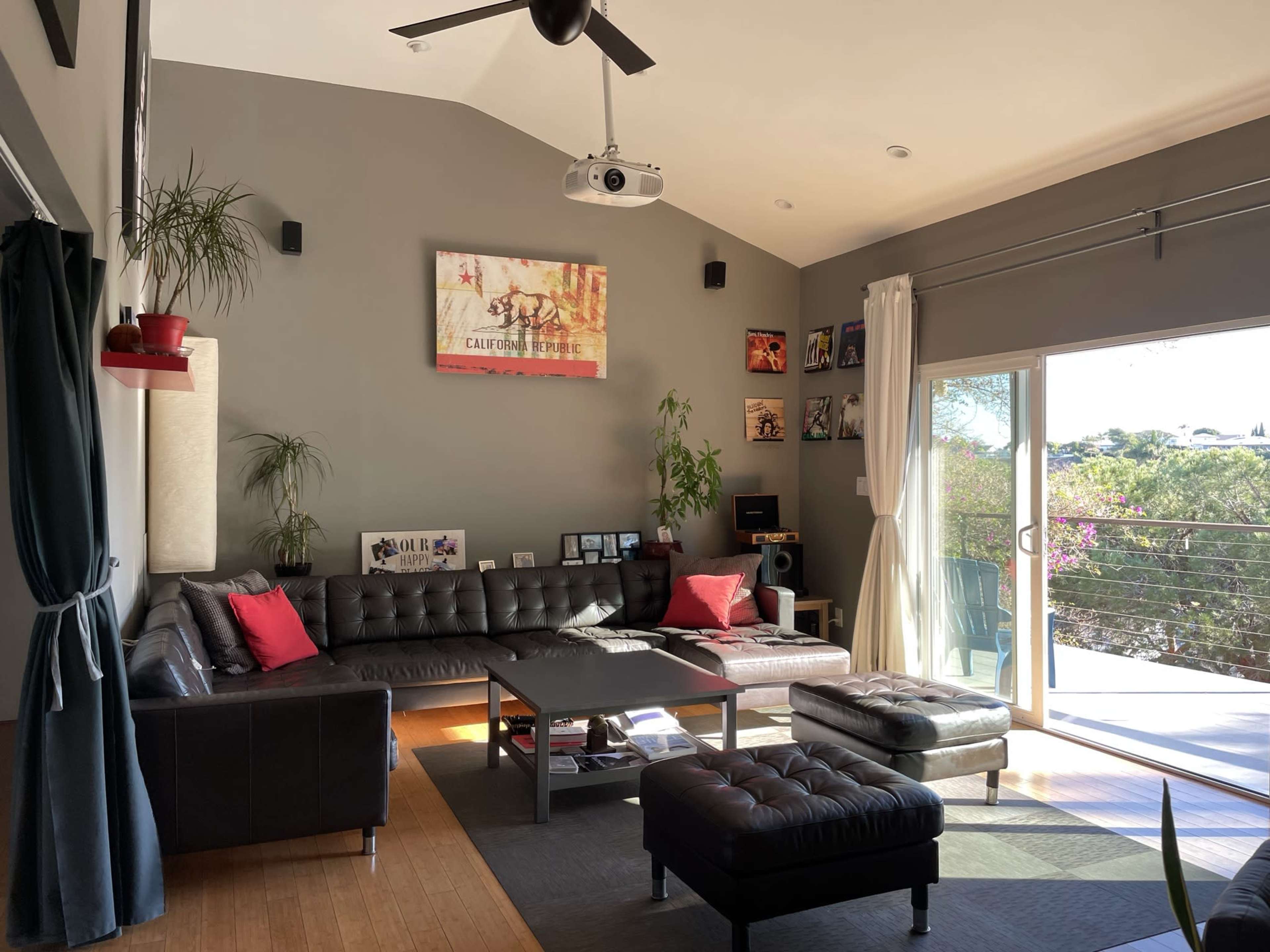 A modern living room with a black leather sectional sofa, a coffee table, and large sliding glass doors leading to a patio.