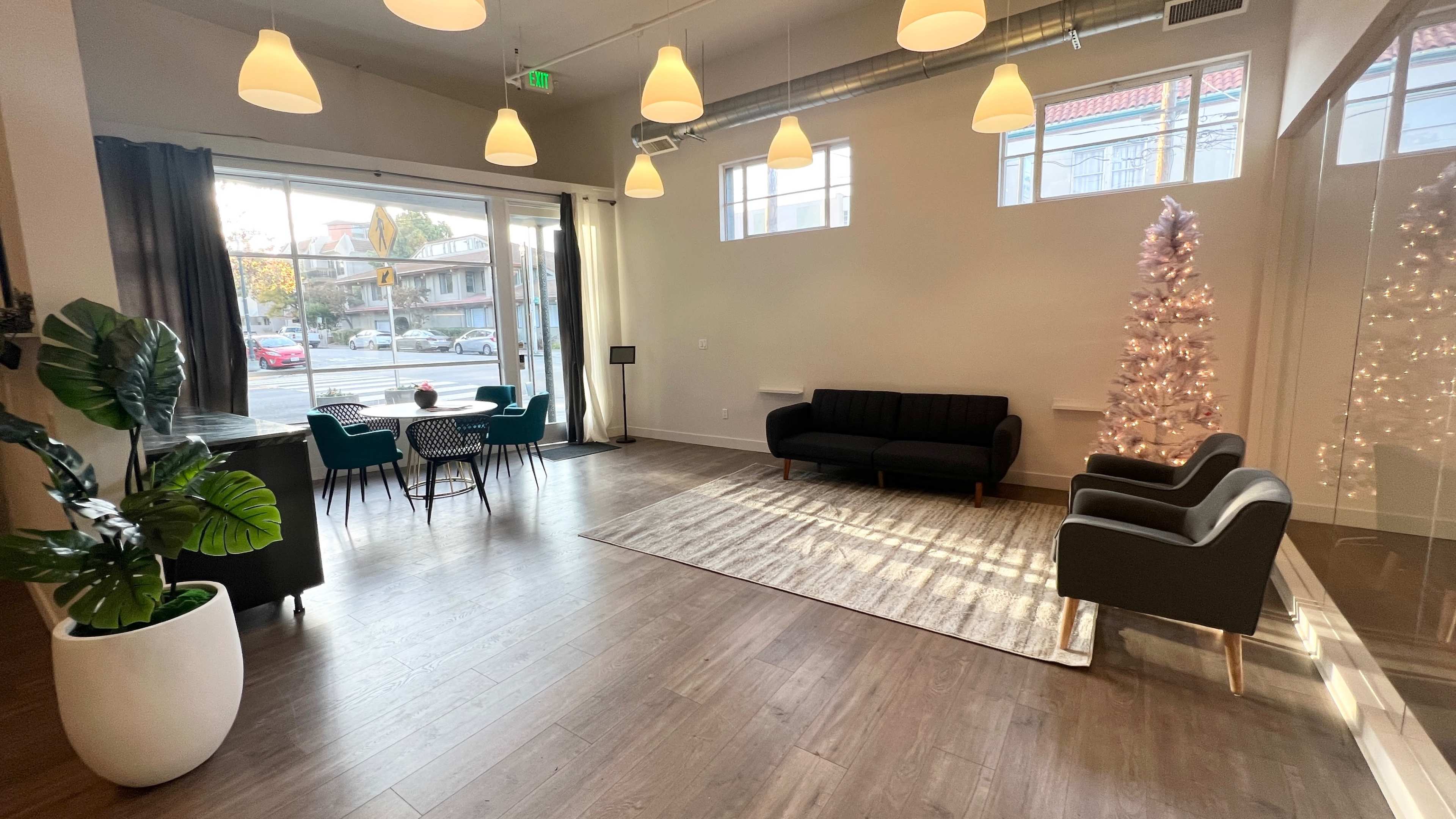 A modern, well-lit interior with a seating area, a dining table, and a decorated Christmas tree in the corner.