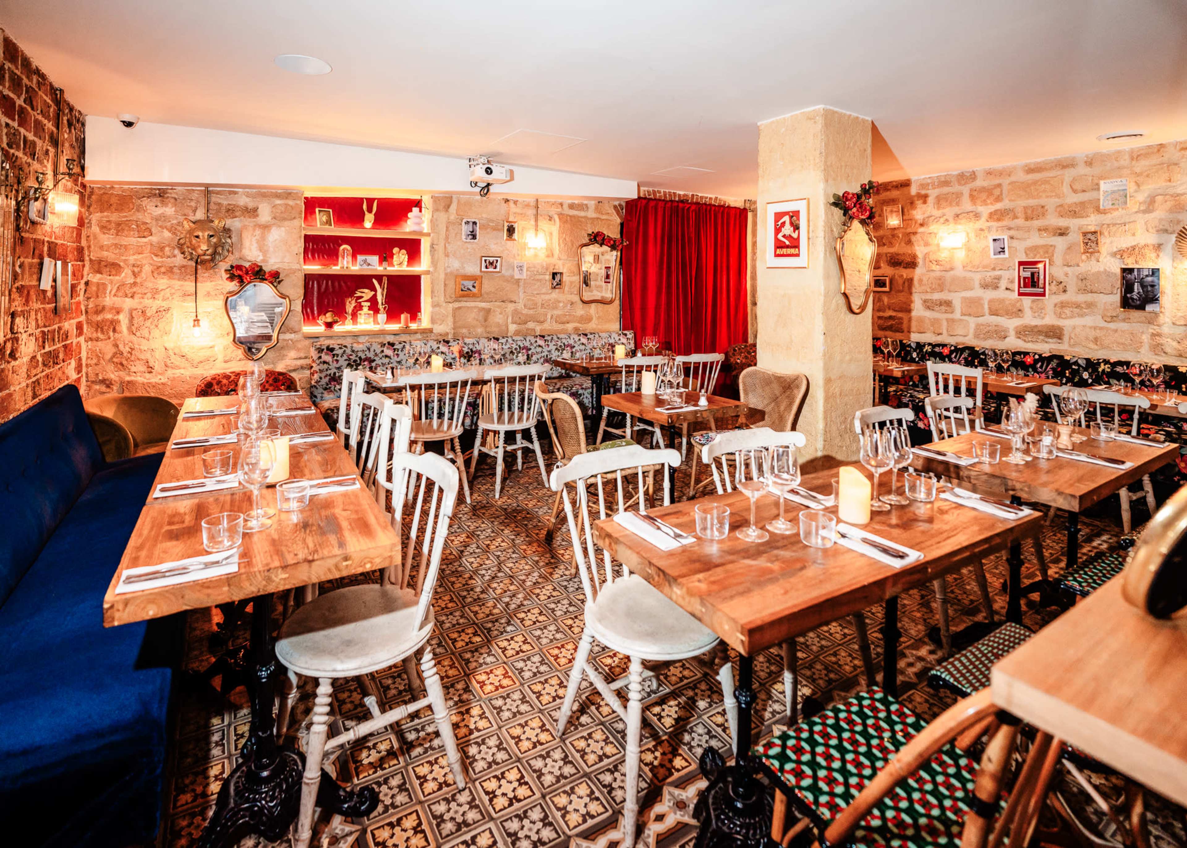 A restaurant interior with wooden tables, white chairs, patterned flooring, and decorative elements on the walls.