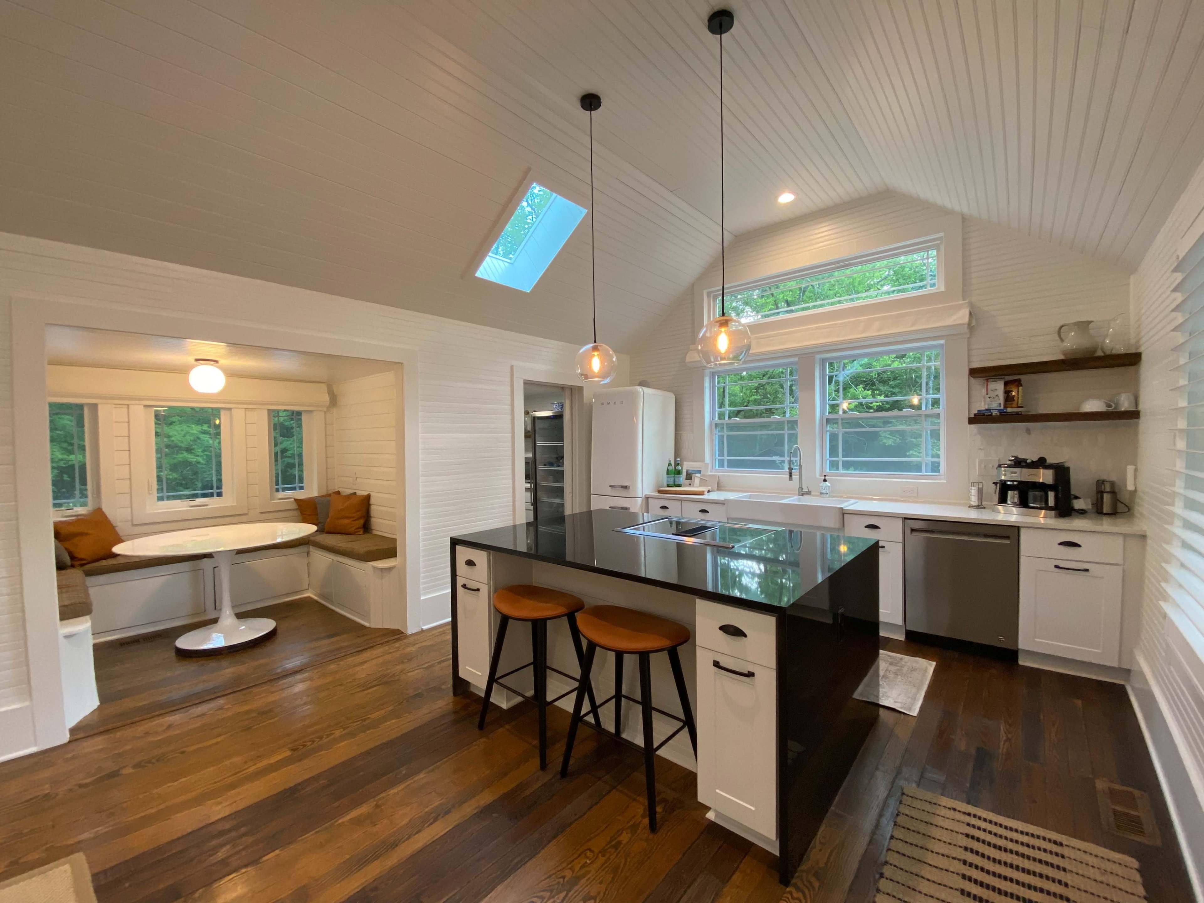 A modern kitchen with a central island, breakfast nook, and large windows letting in natural light.