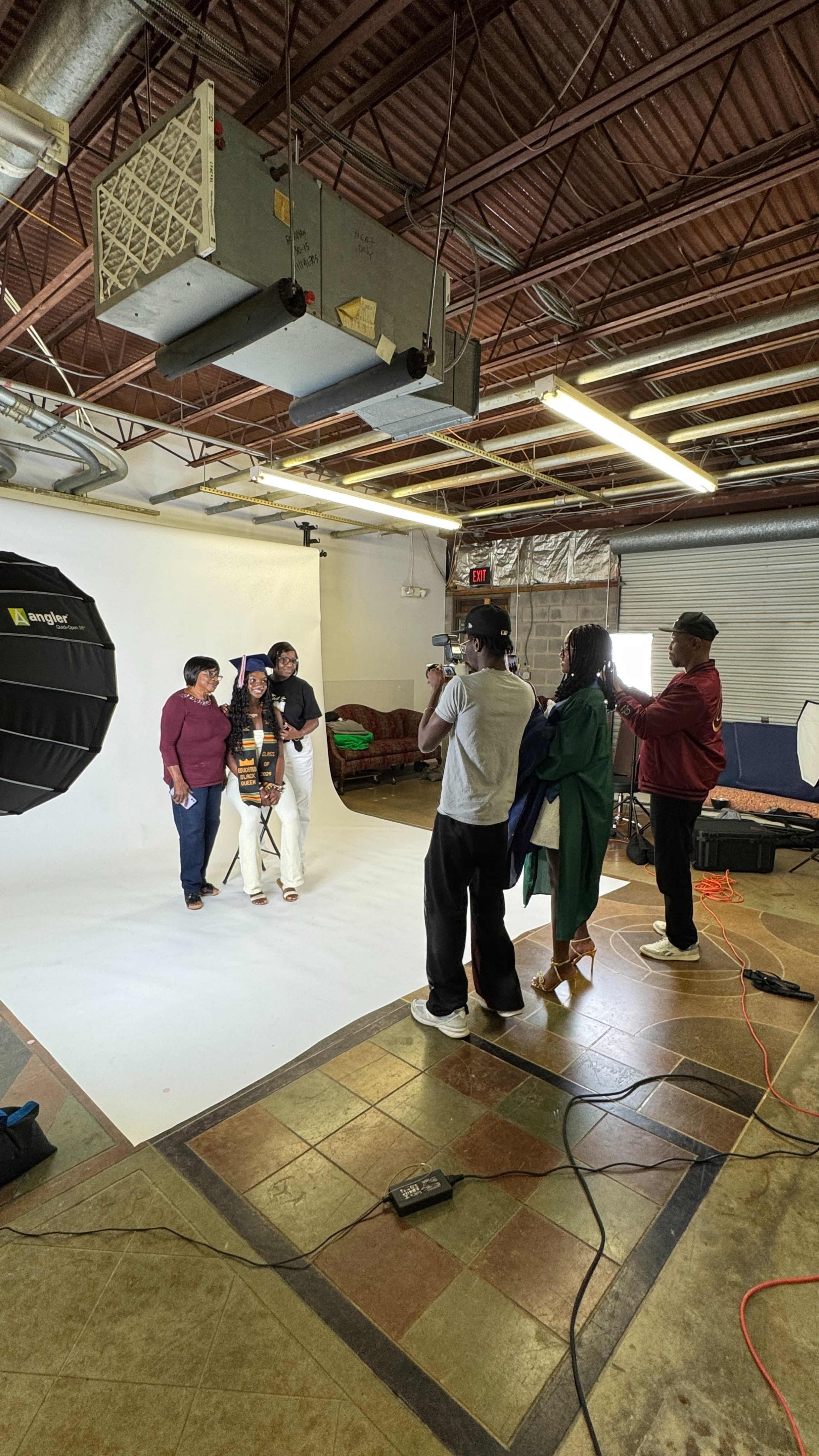 A group of five people poses for a photo in a brightly lit studio with a white backdrop and various photography equipment.
