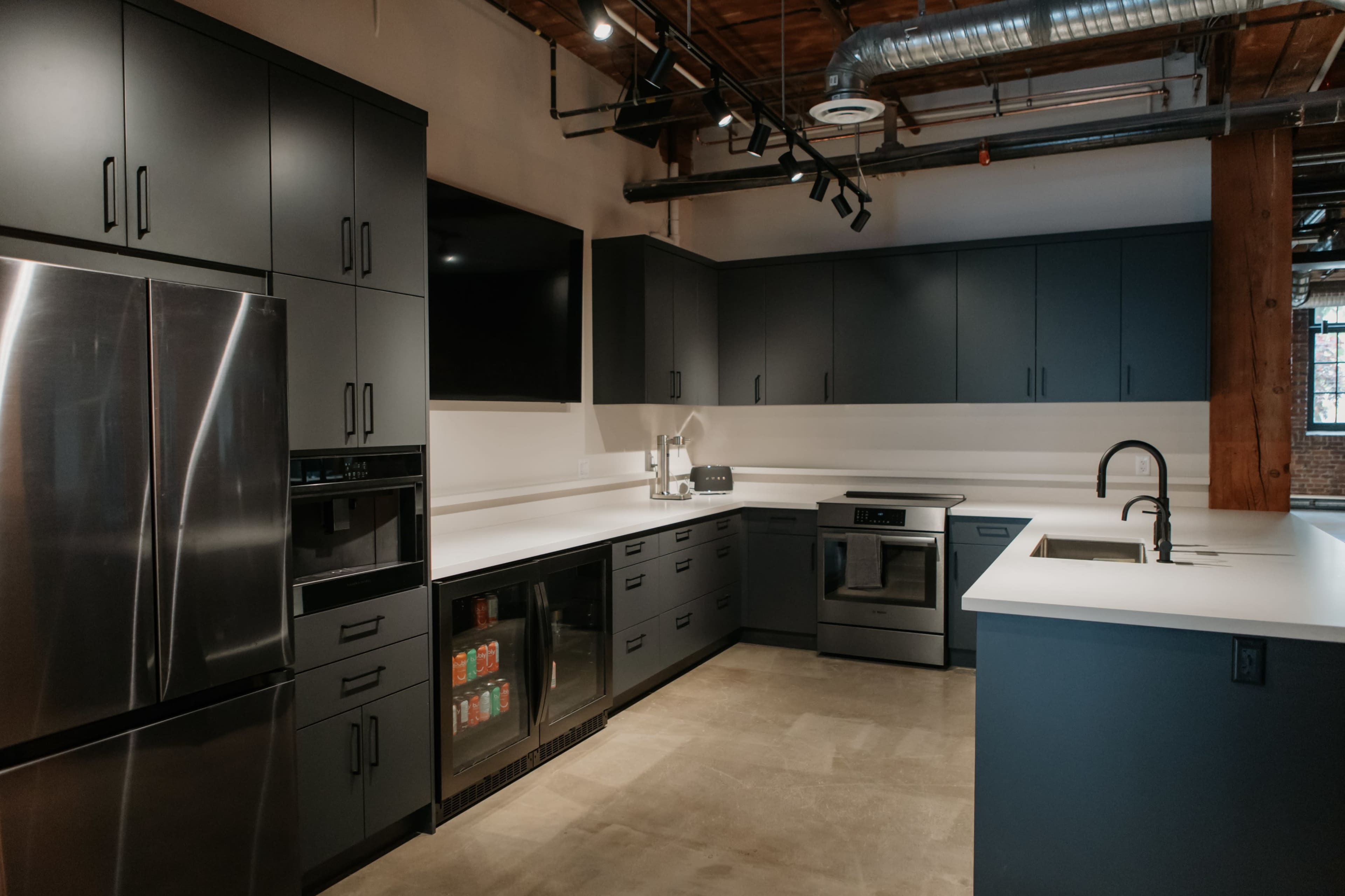 The image shows a modern kitchen featuring dark cabinetry, stainless steel appliances, and a white countertop.