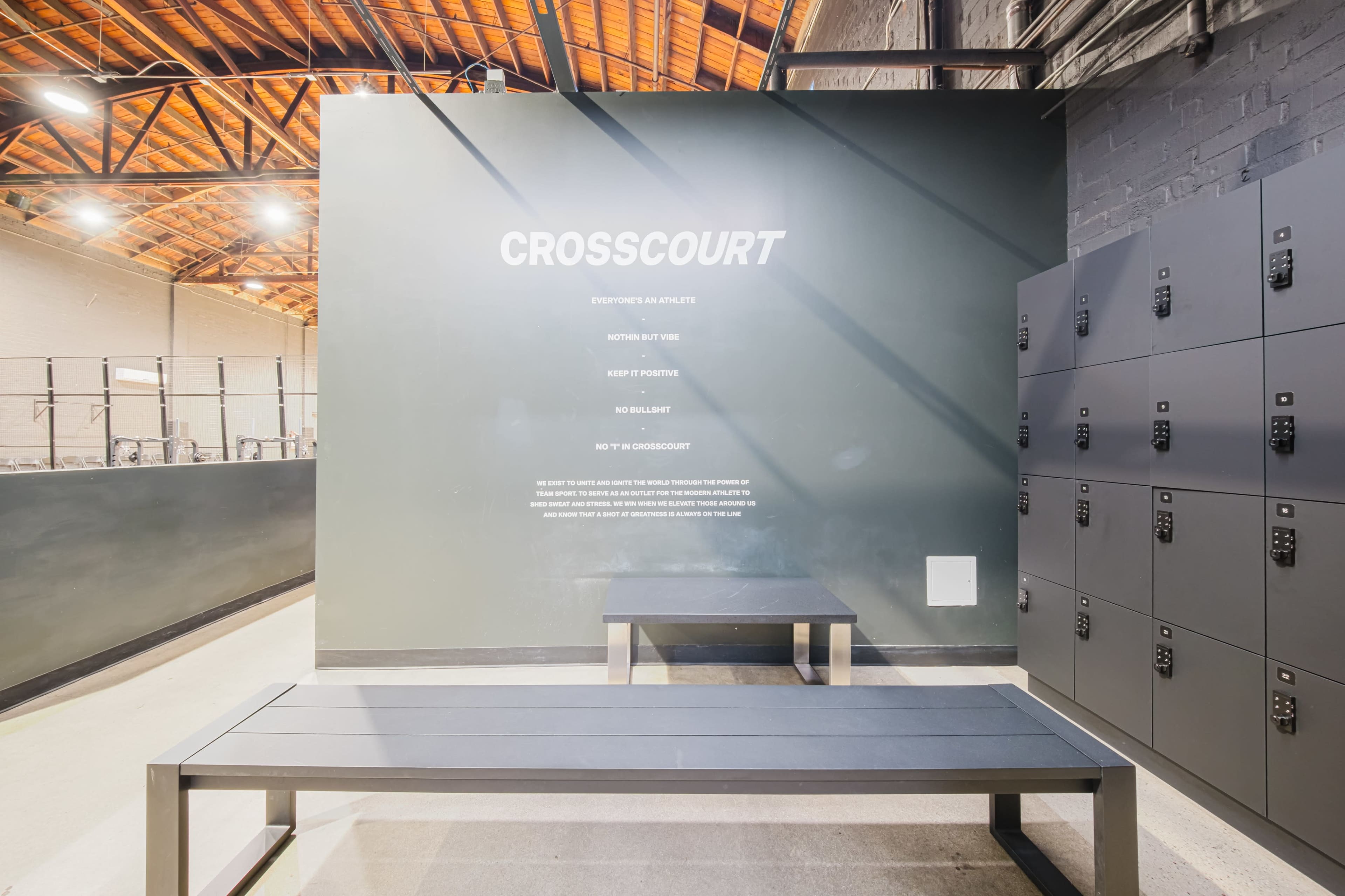 The image shows a modern locker area with a bench and lockers, featuring the word "CROSSCOURT" prominently displayed on the wall.