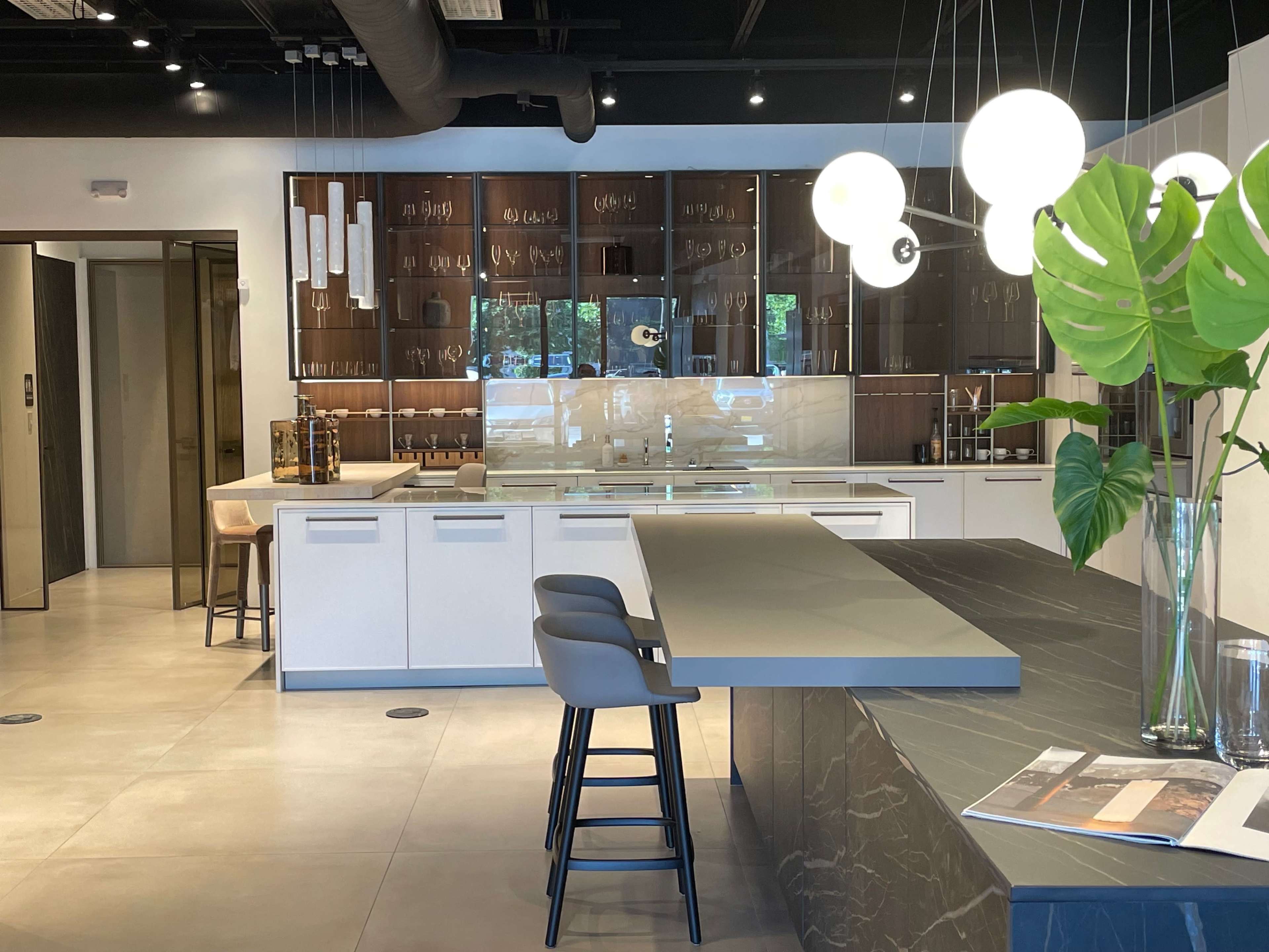 A modern kitchen with a central island, sleek cabinetry, and a stylish dining area illuminated by pendant lights.