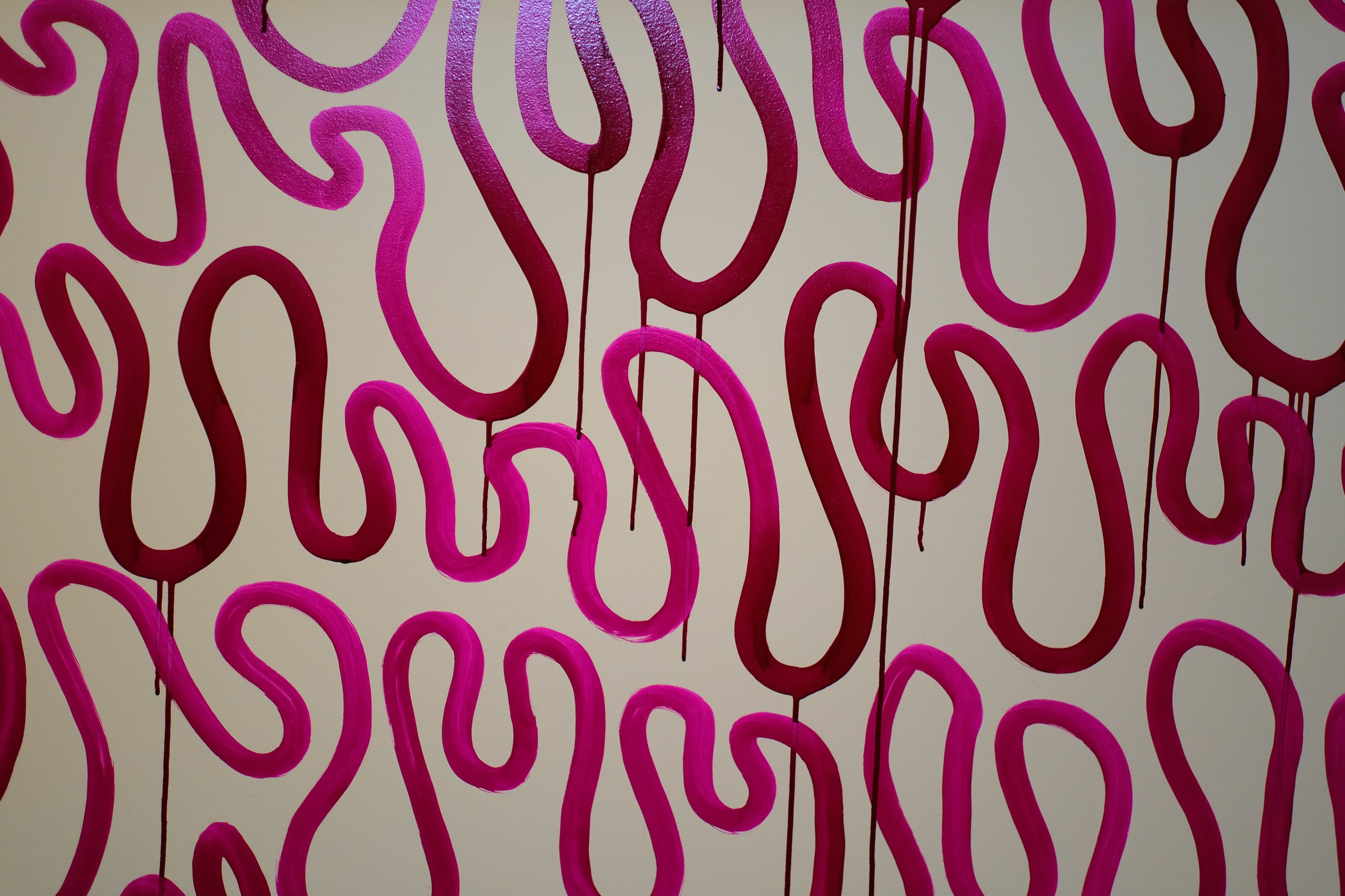 A wall covered in an abstract mural featuring intertwined pink and maroon squiggly lines.