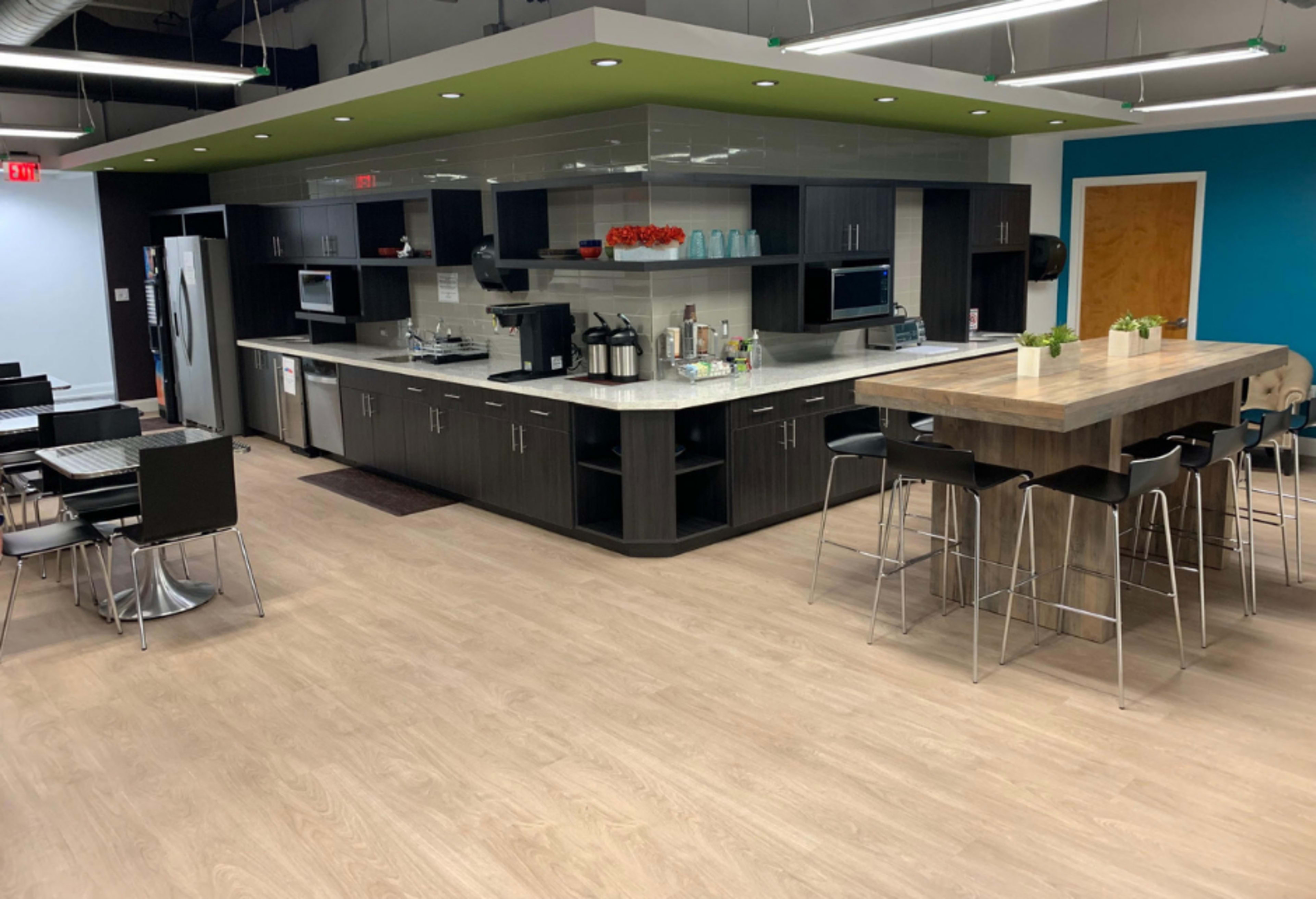 The image shows a modern kitchen and dining area with a large island, stainless steel appliances, and various seating options.