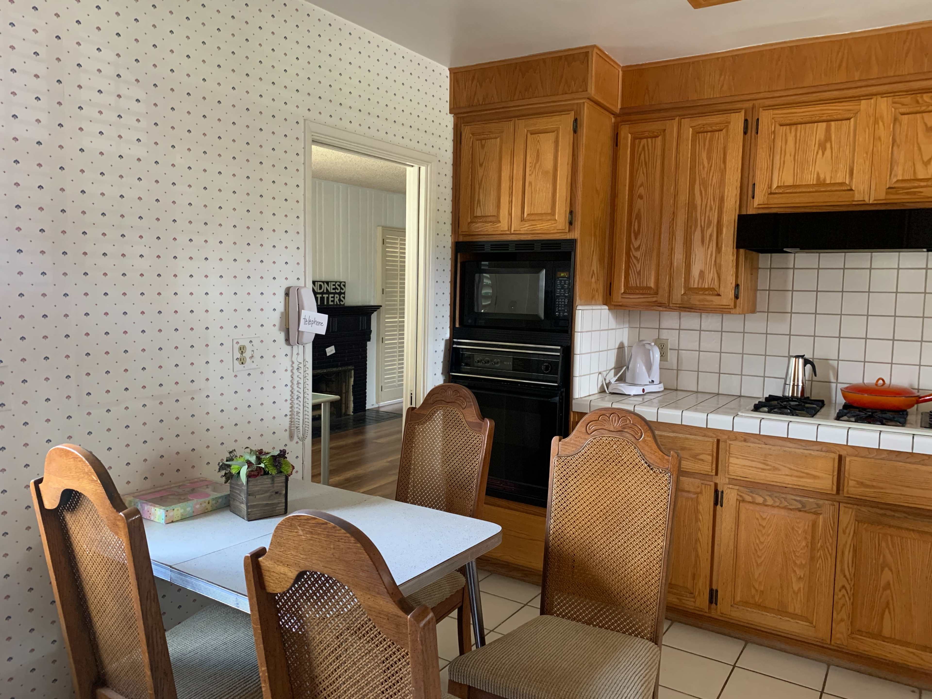 A kitchen featuring wooden cabinetry, a tiled floor, and a small dining table with four chairs.