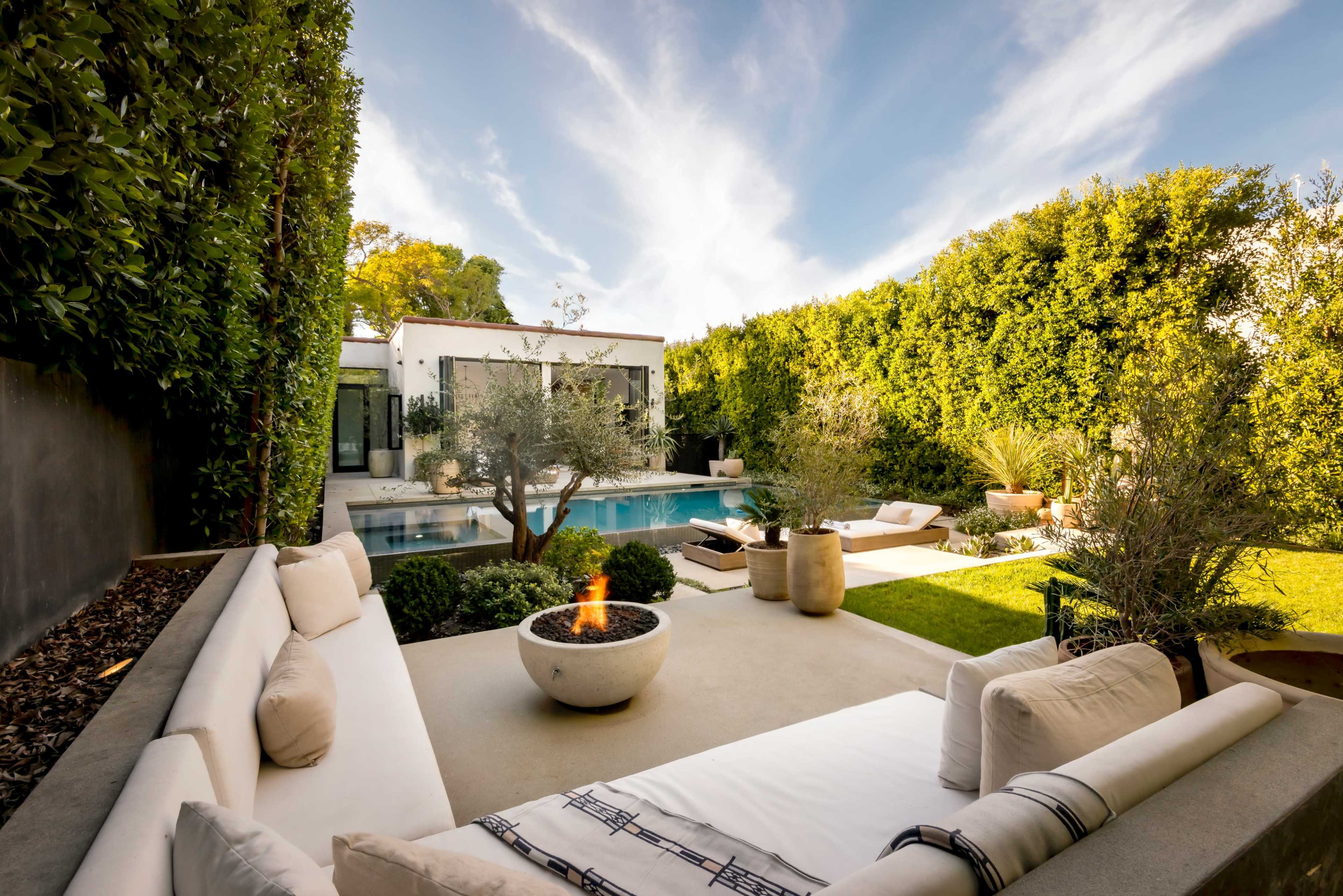The scene features a modern backyard with a swimming pool, seating area, and lush greenery surrounding the space.
