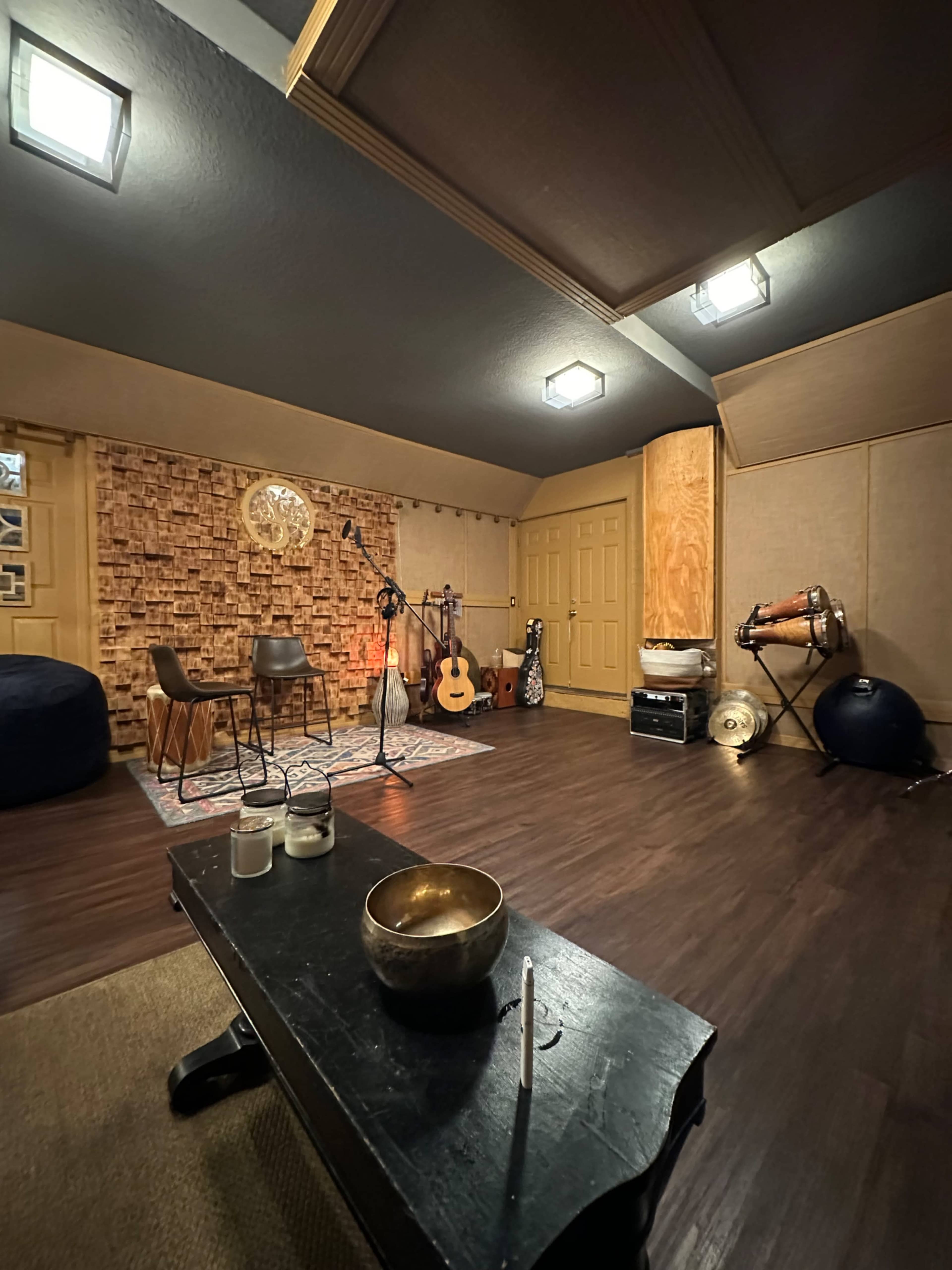 A music room with a wooden floor, soundproof walls, various instruments, and seating arranged for recording or practice.