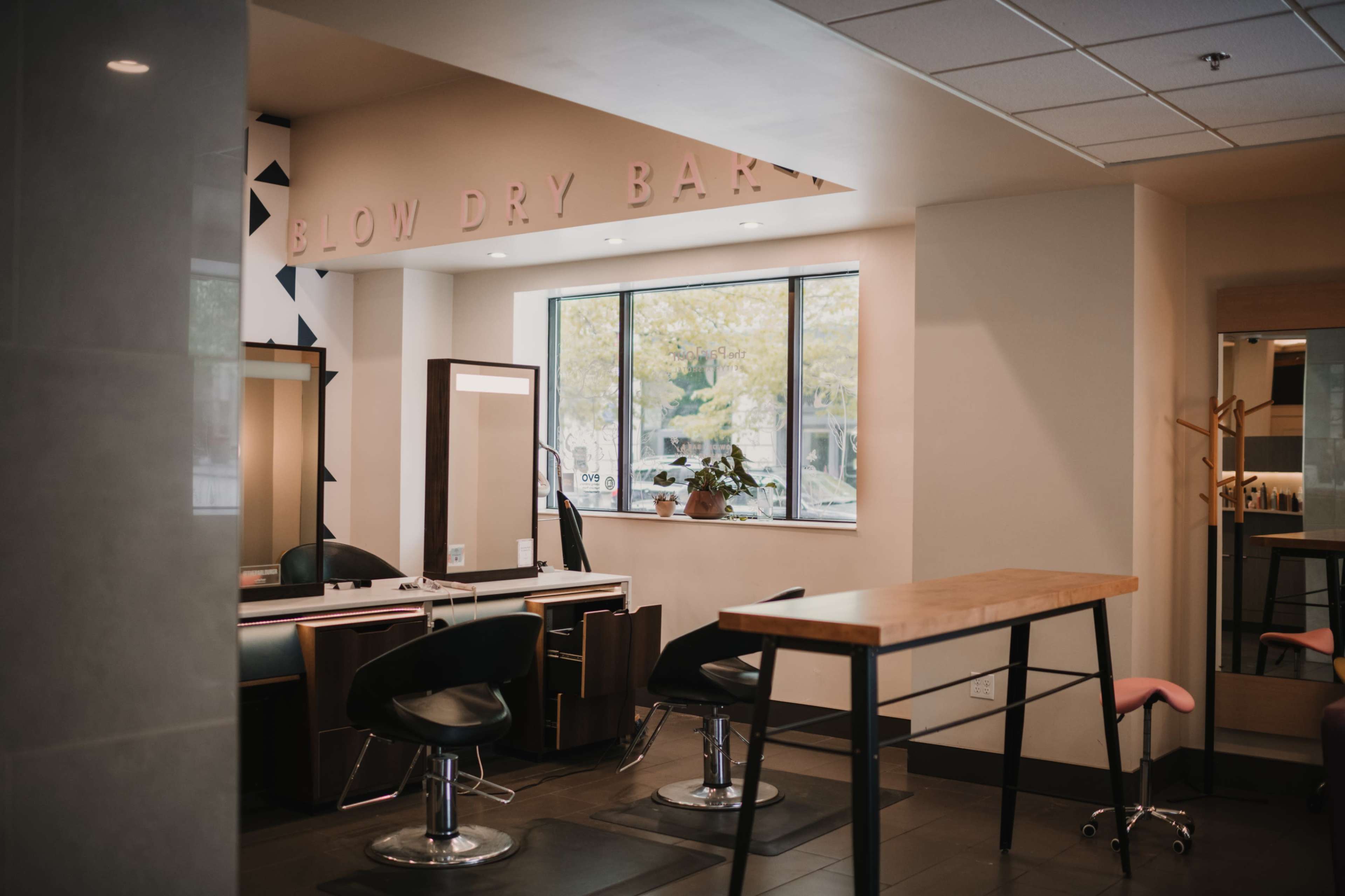 A modern hair salon interior featuring styling stations, mirrors, and a central table.