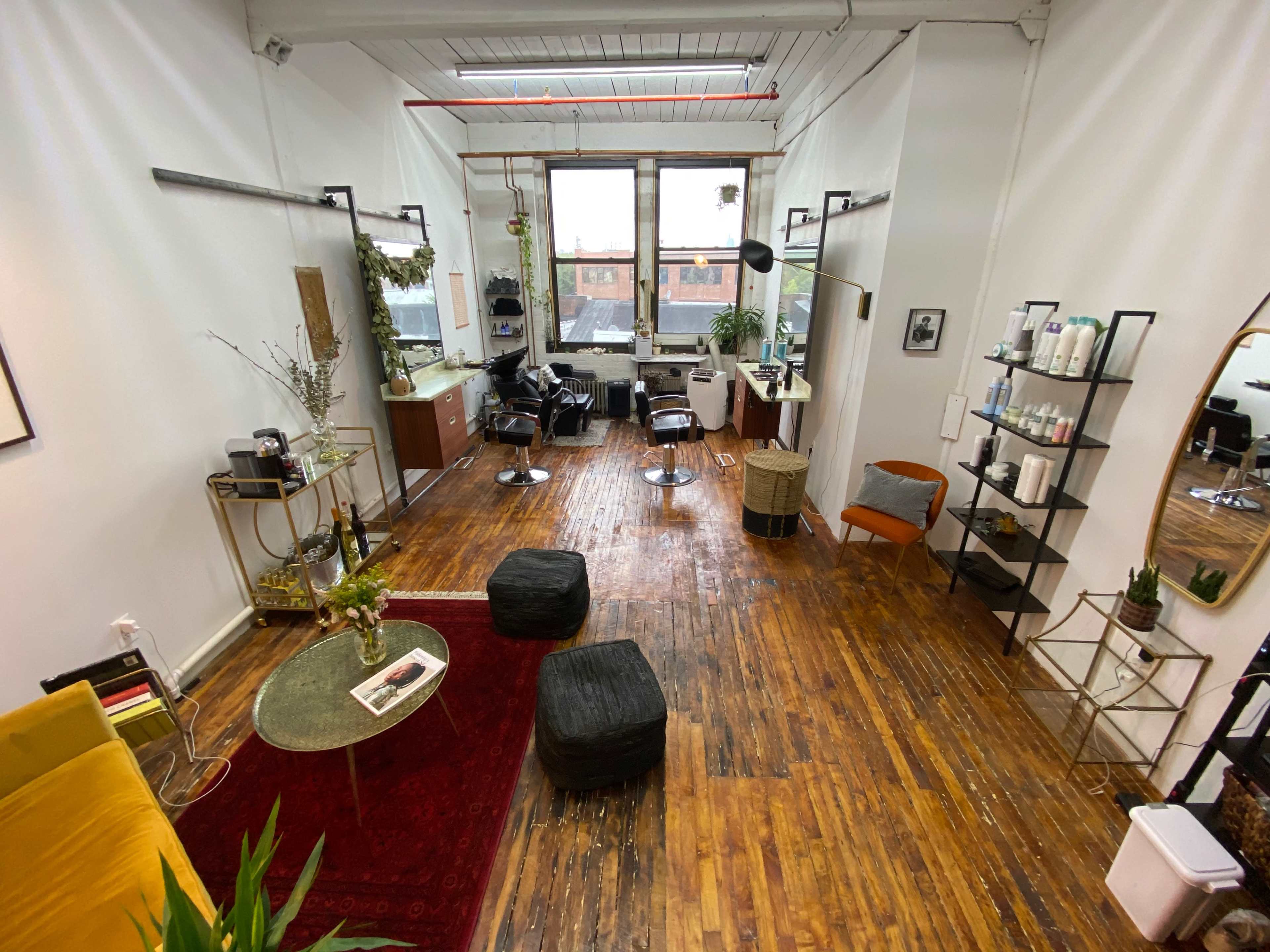 A modern, open interior space with wooden floors, featuring seating areas, a coffee table, and large windows that allow natural light to enter.