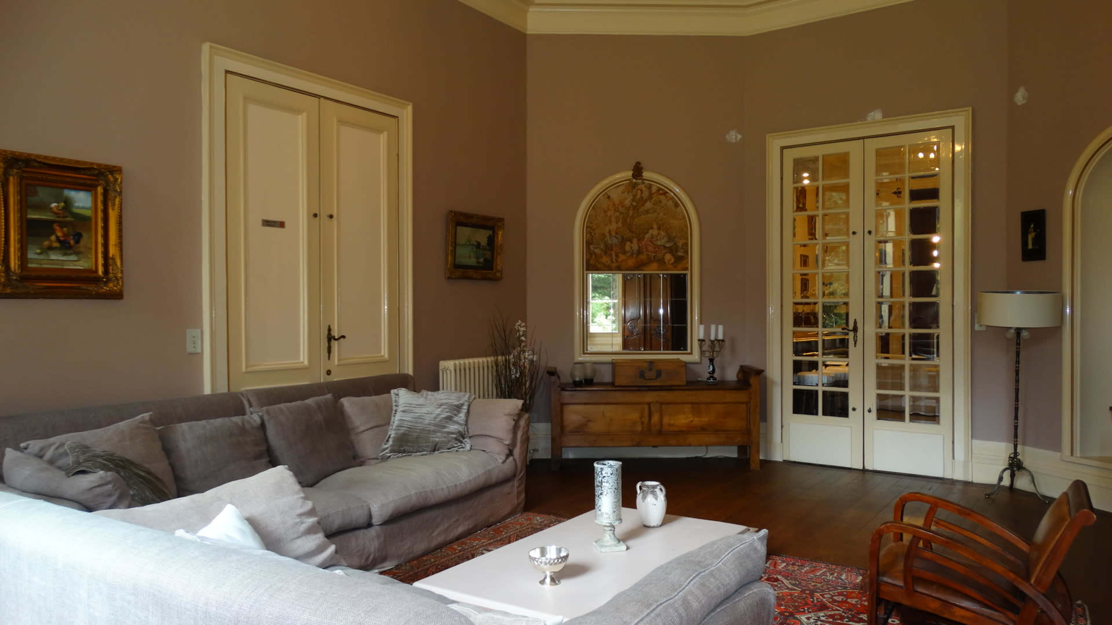 The image depicts a cozy living room featuring a gray sofa, wooden furniture, and decorative interior elements, including artwork and a mirror.