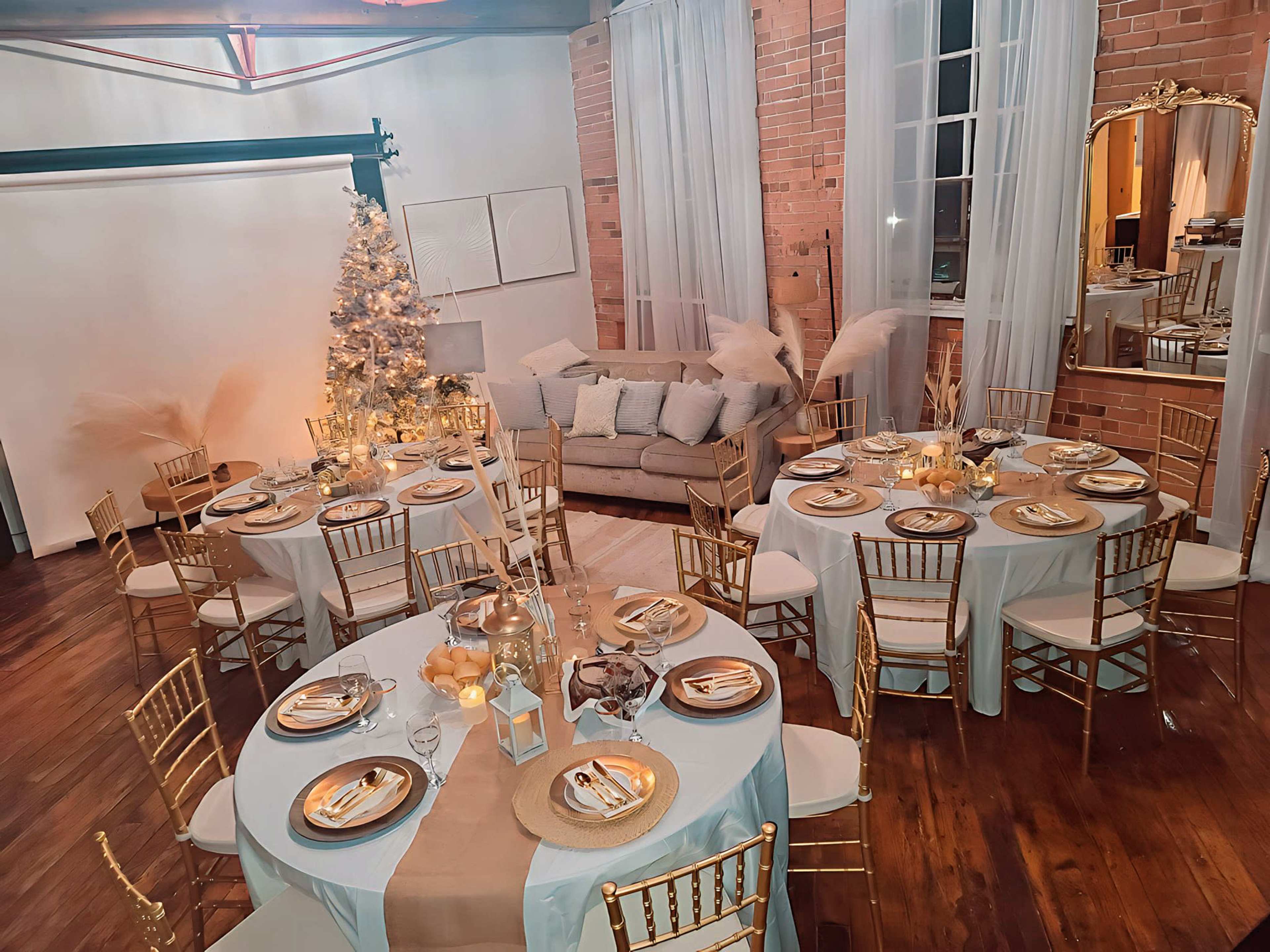 The scene features a beautifully arranged dining area with round tables set for a formal gathering, decorated with gold accents and a Christmas tree in the background.