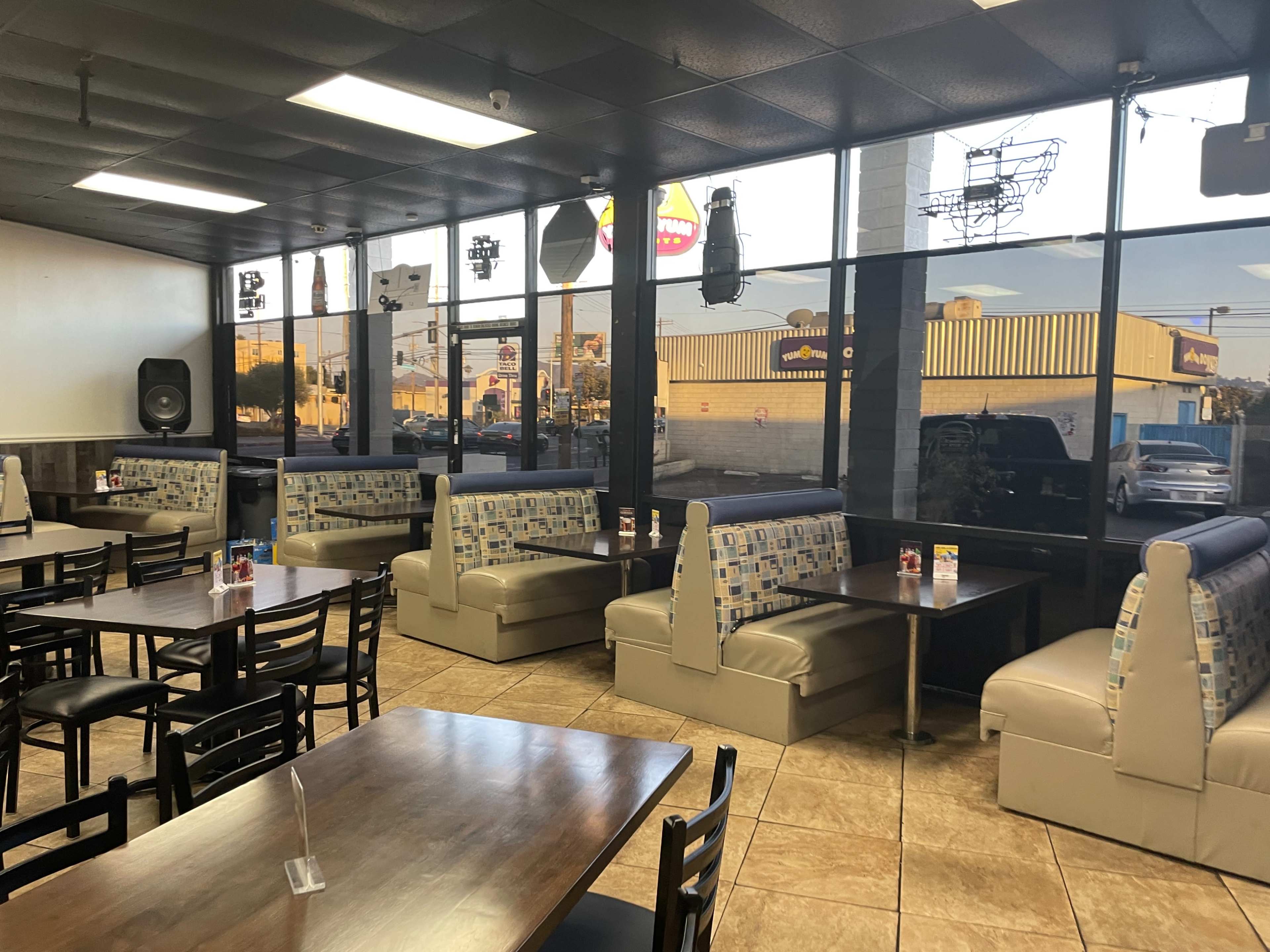 A casual dining area with booths and tables, featuring large windows that provide a view of the outside.