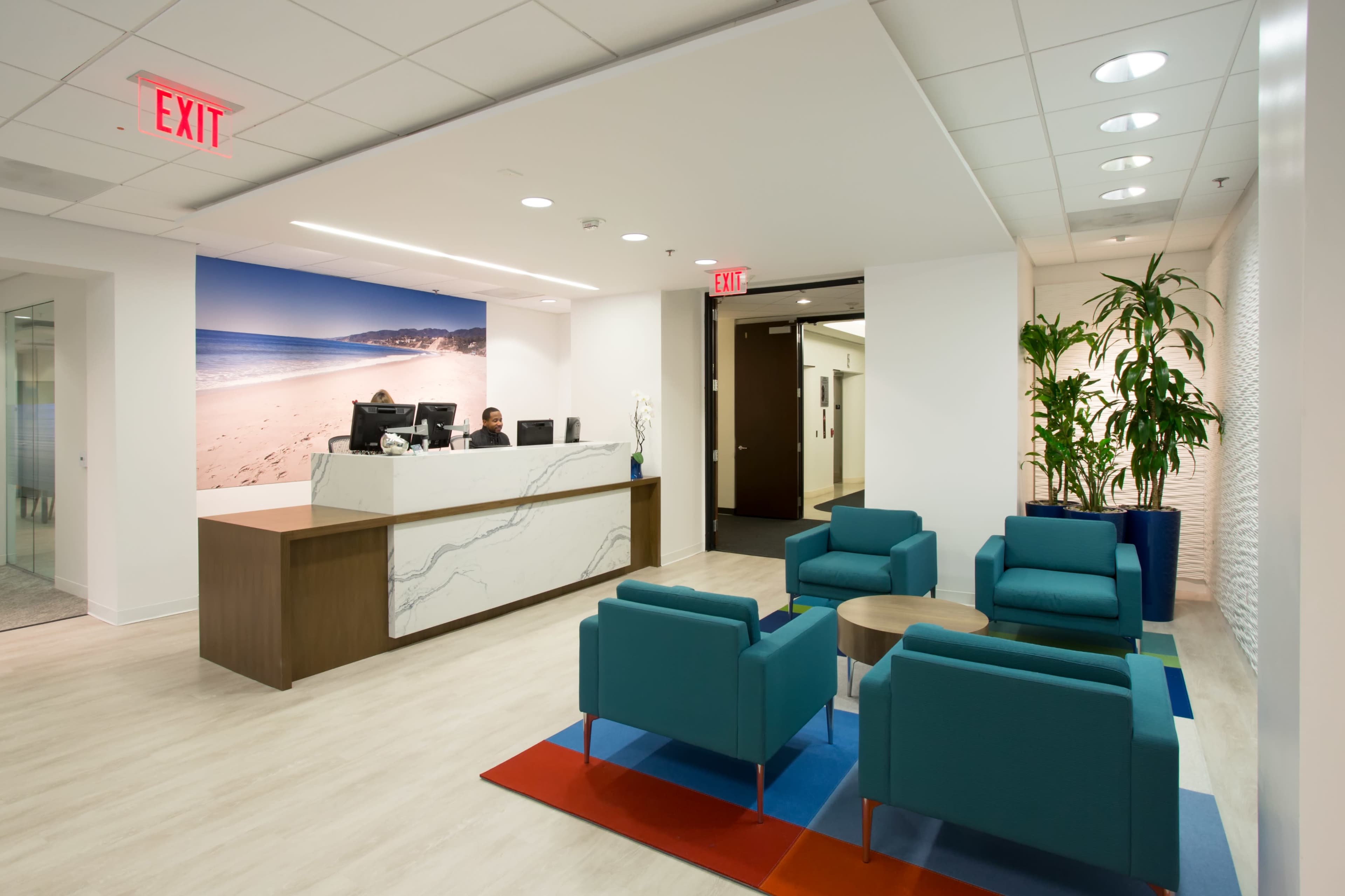 A modern reception area with a front desk, seating, and decorative plants.