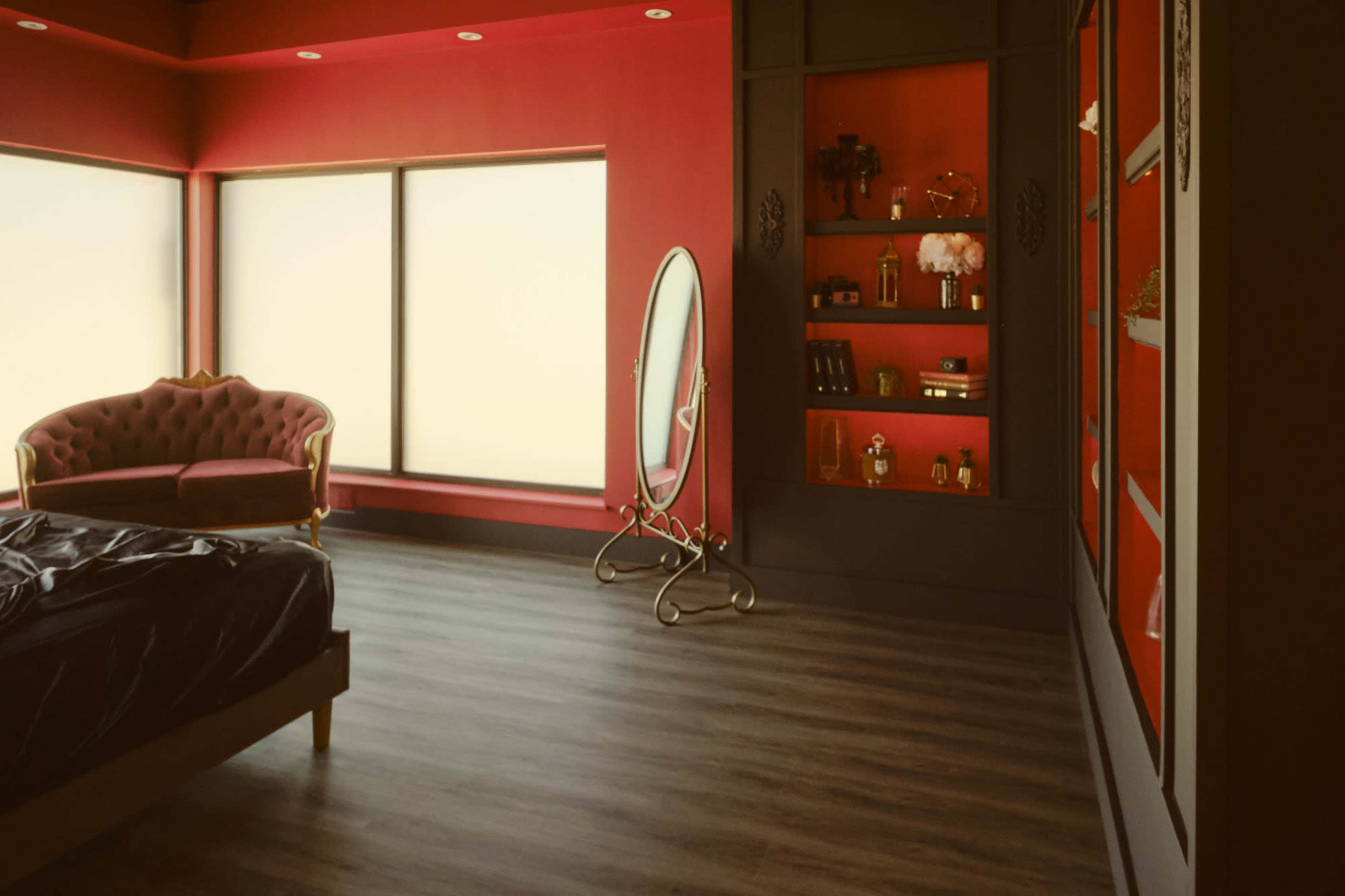 The scene features a stylish bedroom with red walls, a velvet chaise lounge, a large mirror, and a display cabinet filled with decorative items.