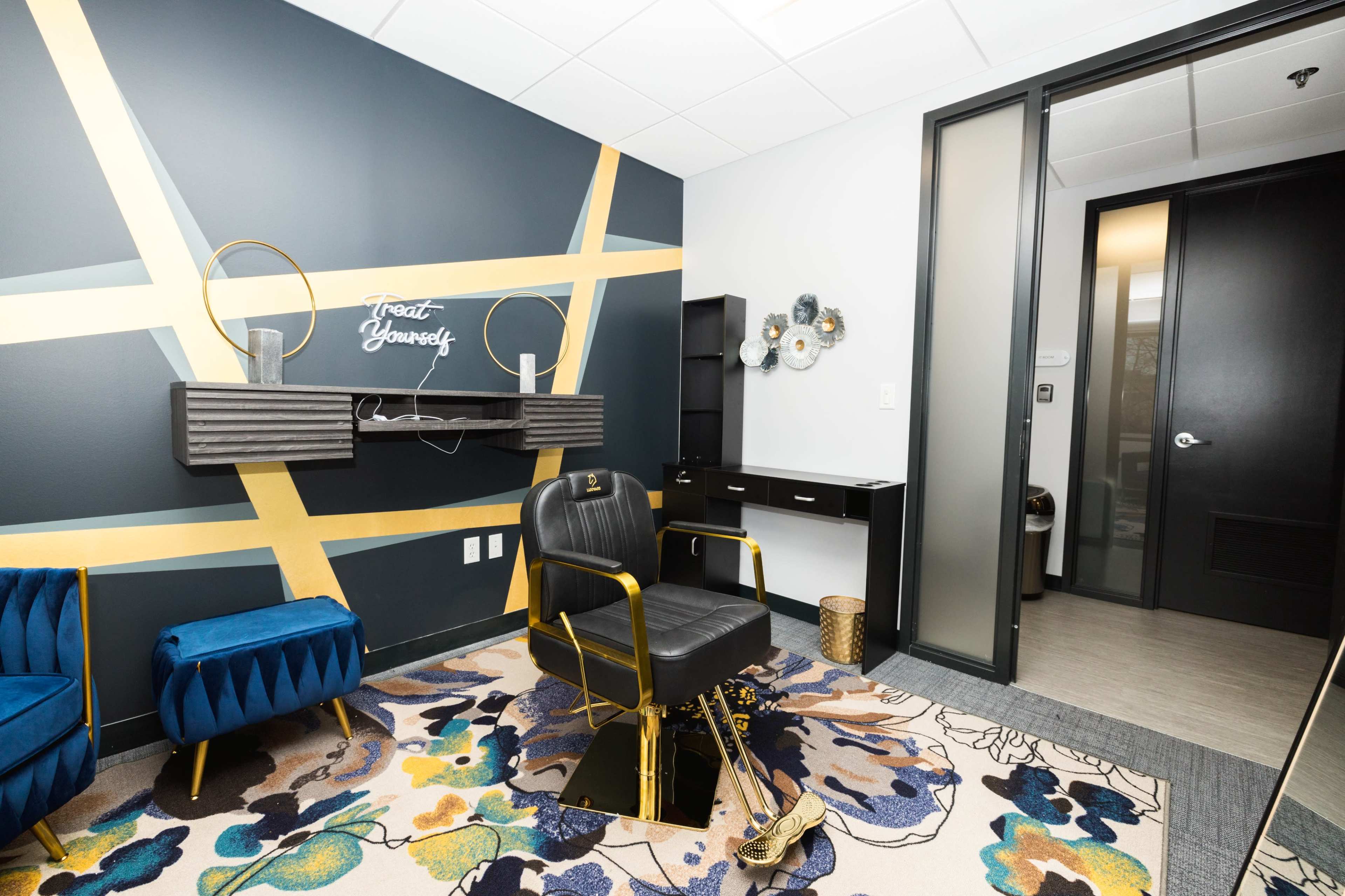 A modern office space featuring a stylish chair and a desk, accented by decorative wall art and a patterned rug.