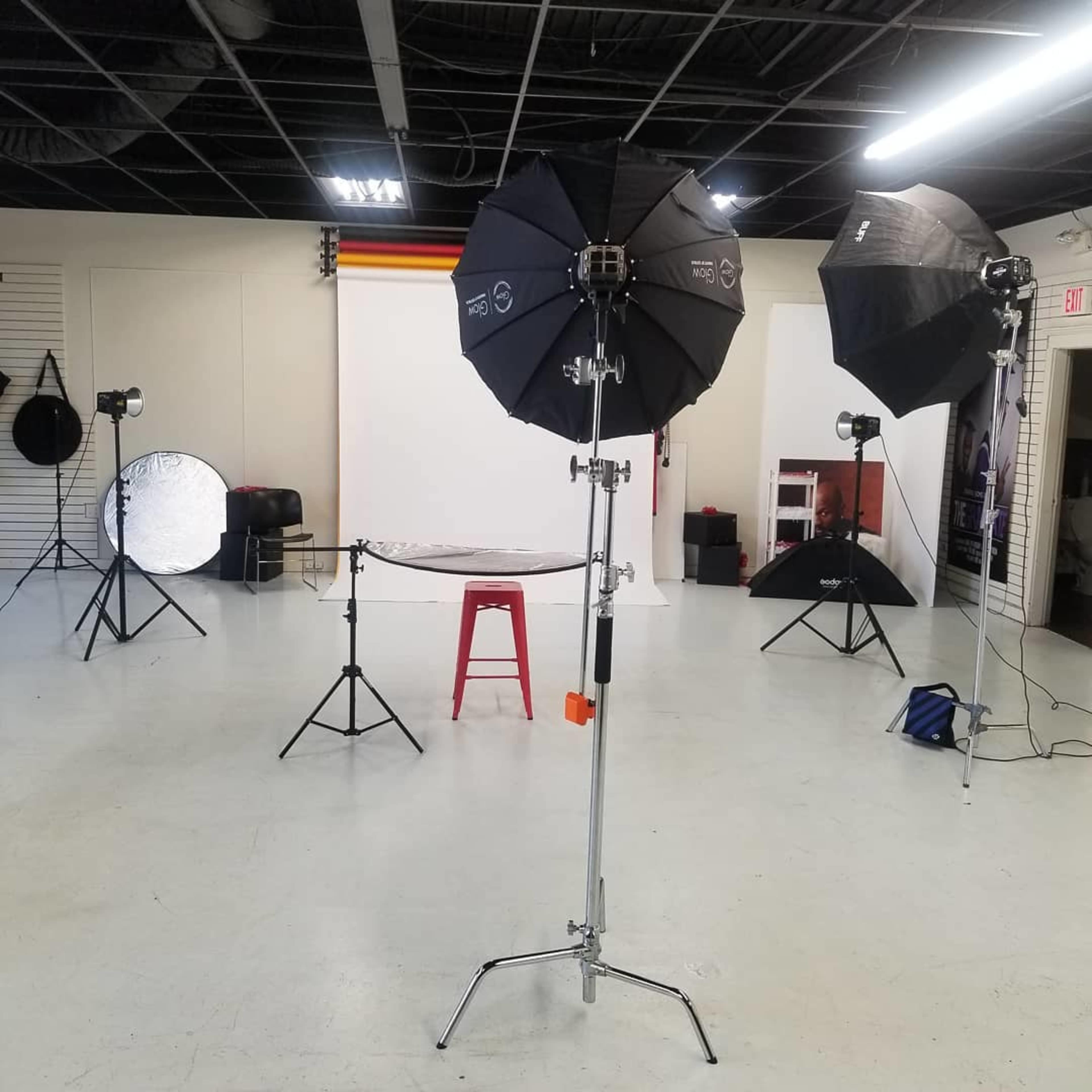 A photography studio setup with lighting equipment, including softboxes and reflectors, arranged around a central empty space for shooting.