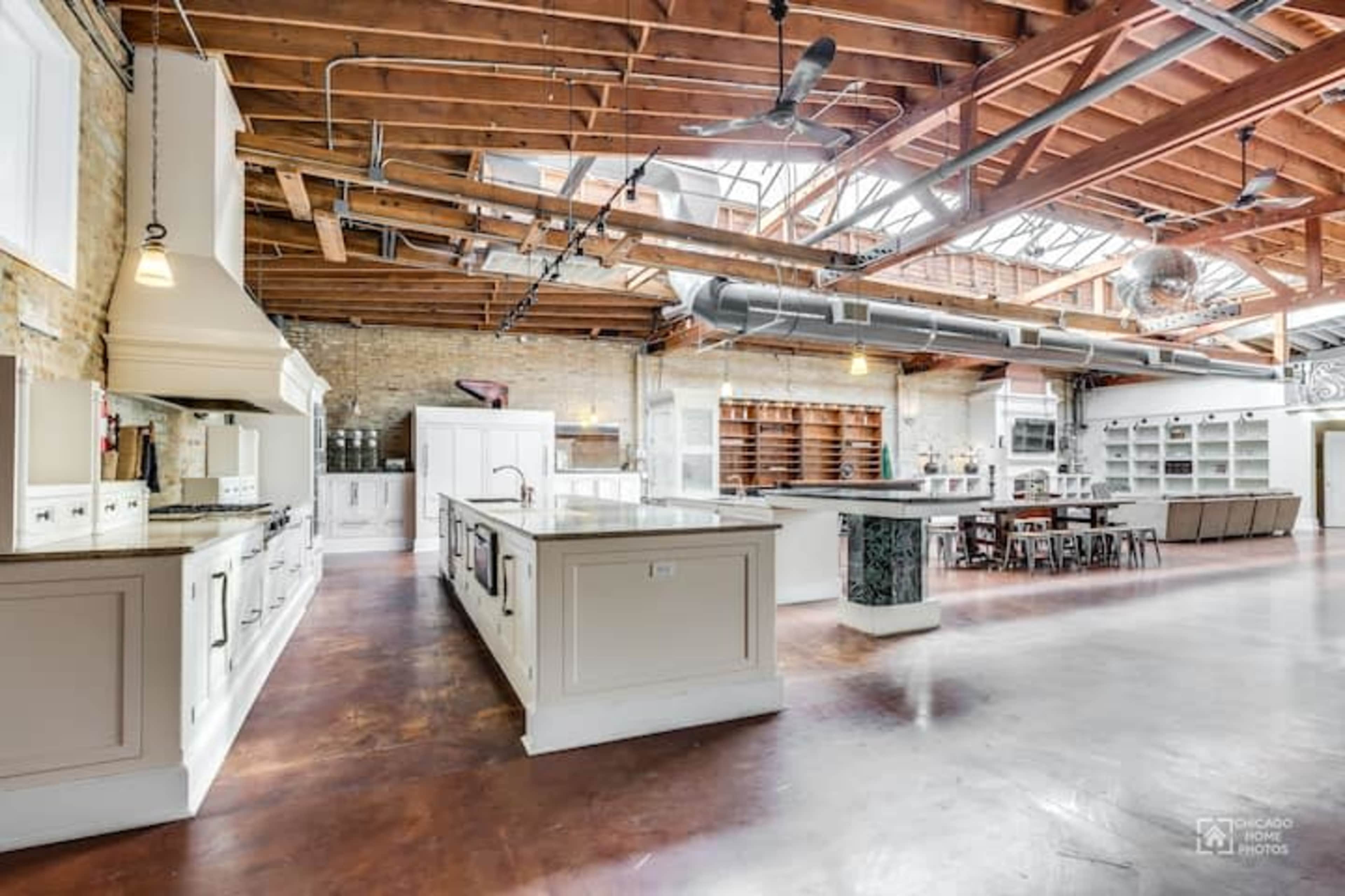 A spacious kitchen area with wooden beams, an island in the center, and ample cabinetry along the walls.