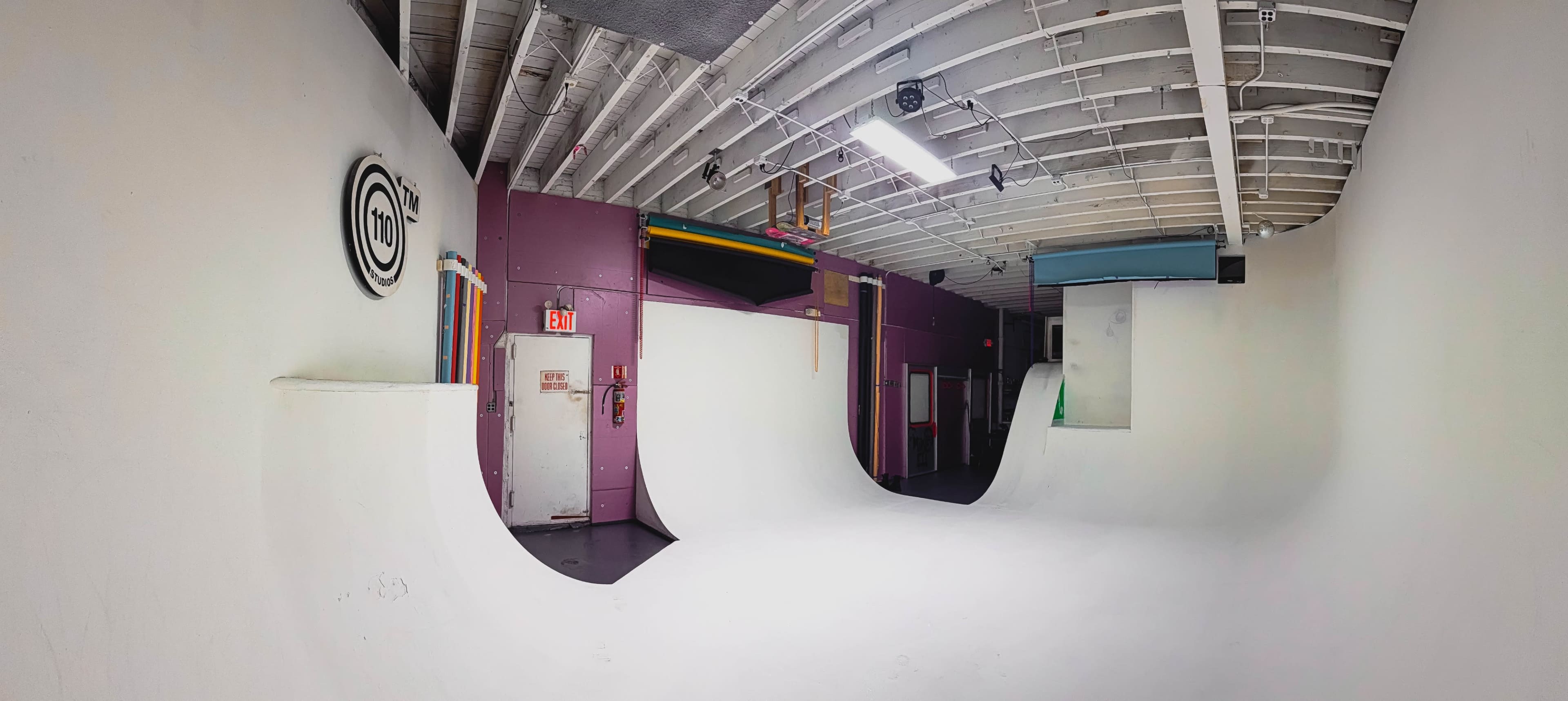 The image shows an indoor skate park with two white half-pipes and purple walls.
