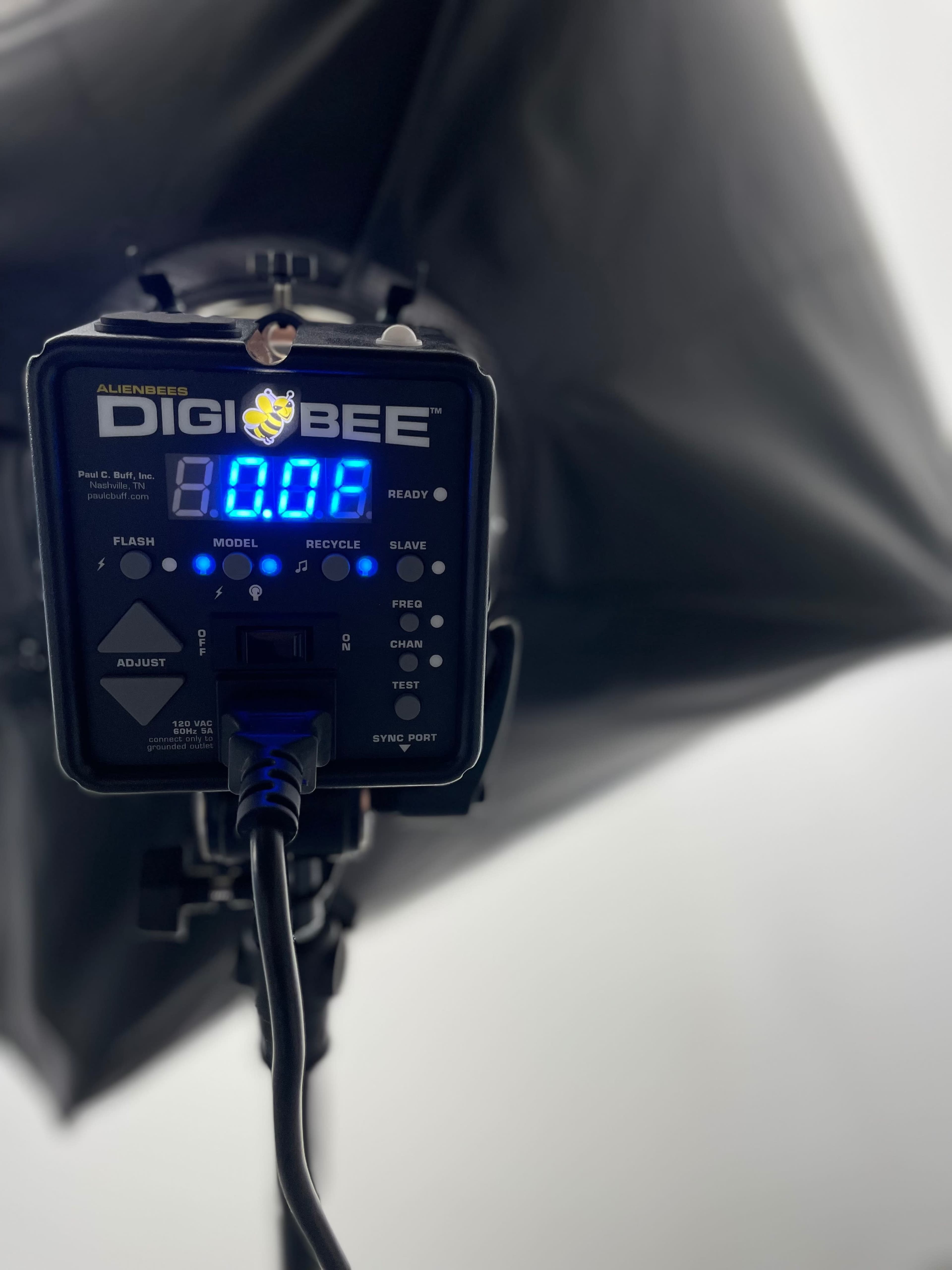 A DigiBee light control unit with a digital display, connected to a softbox diffuser.