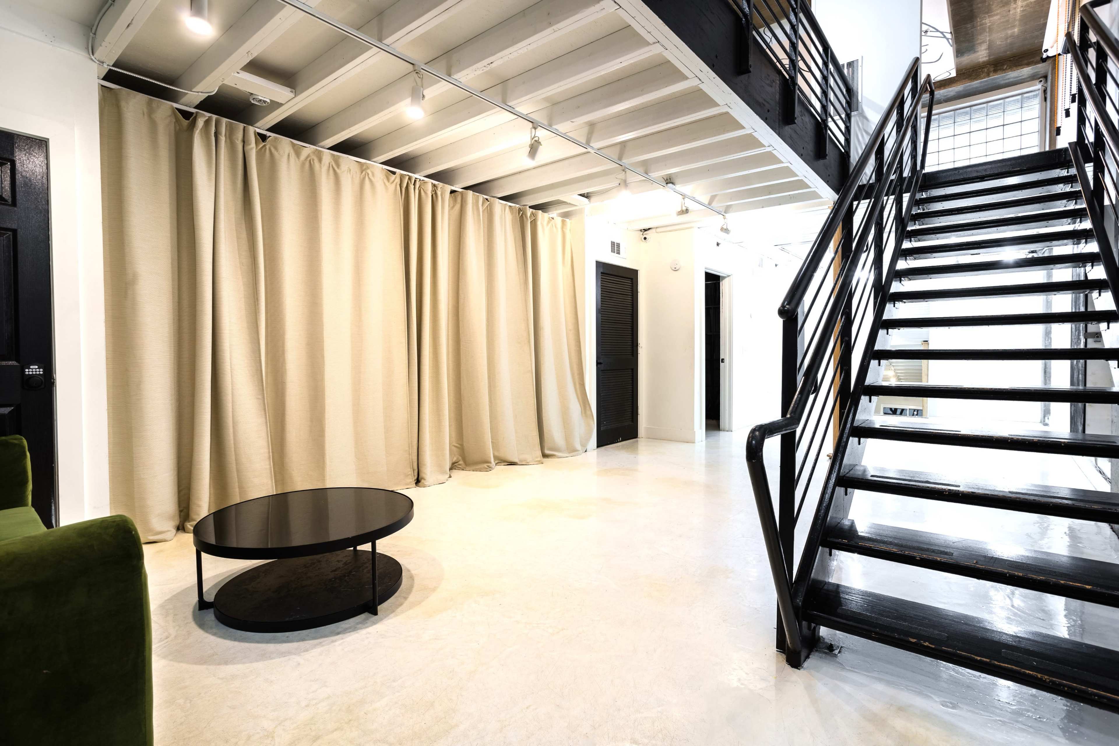 A modern interior space featuring a staircase, a black circular coffee table, and a curtain partition.