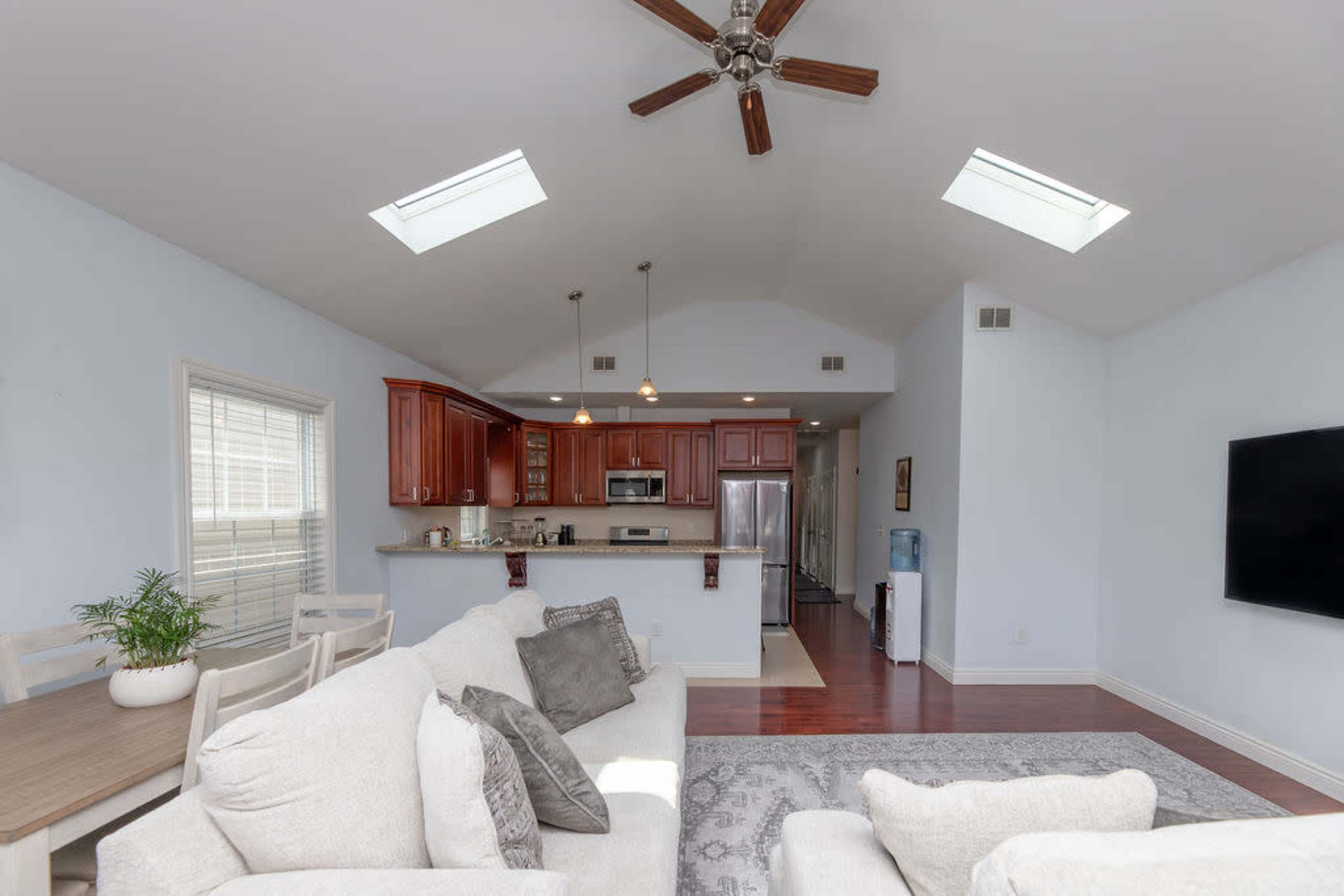 A spacious, well-lit living area with a kitchen featuring wooden cabinets and stainless steel appliances, alongside a comfortable seating area.