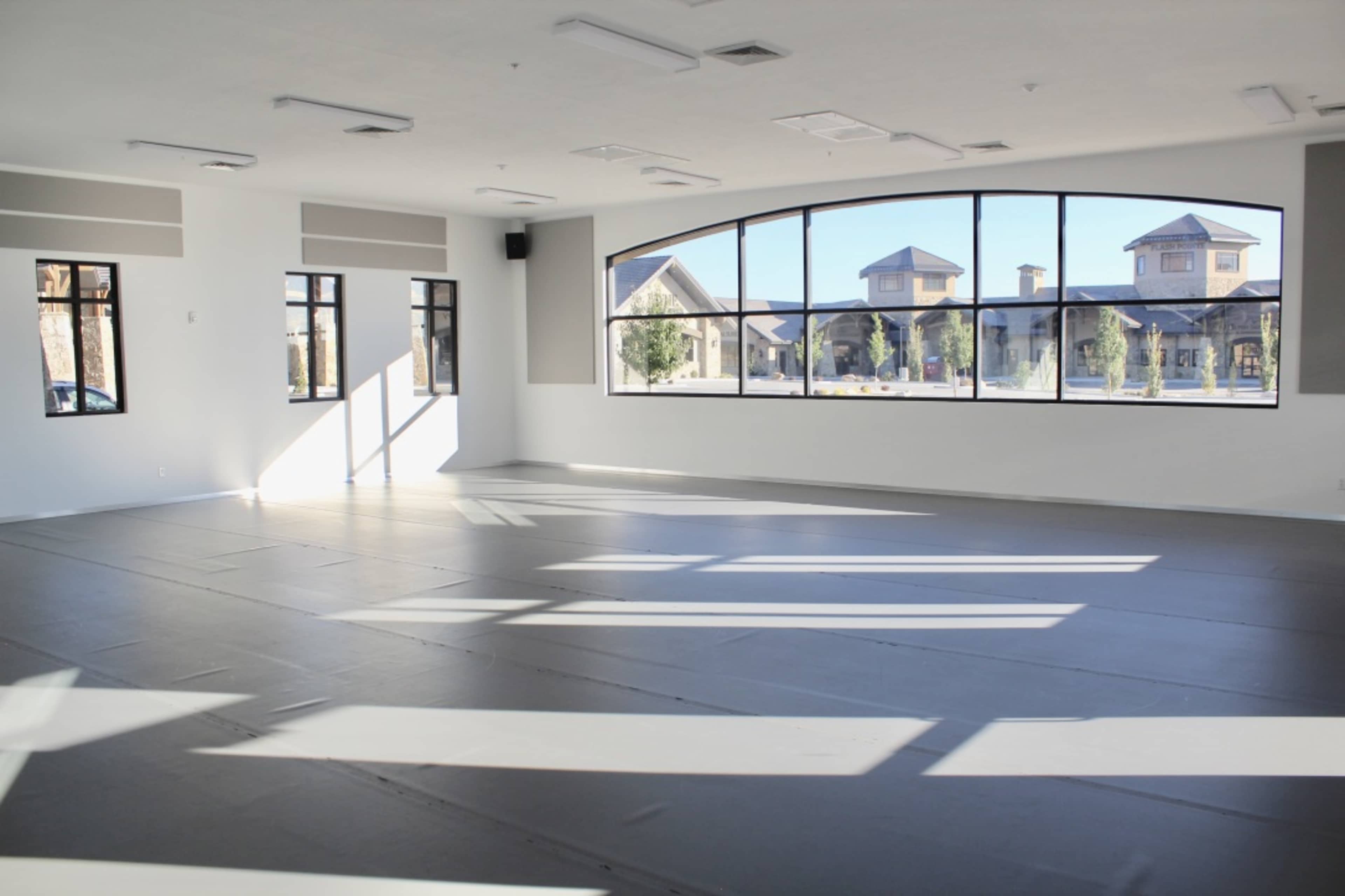 A spacious room with a smooth gray floor and large windows that allow natural light to enter.