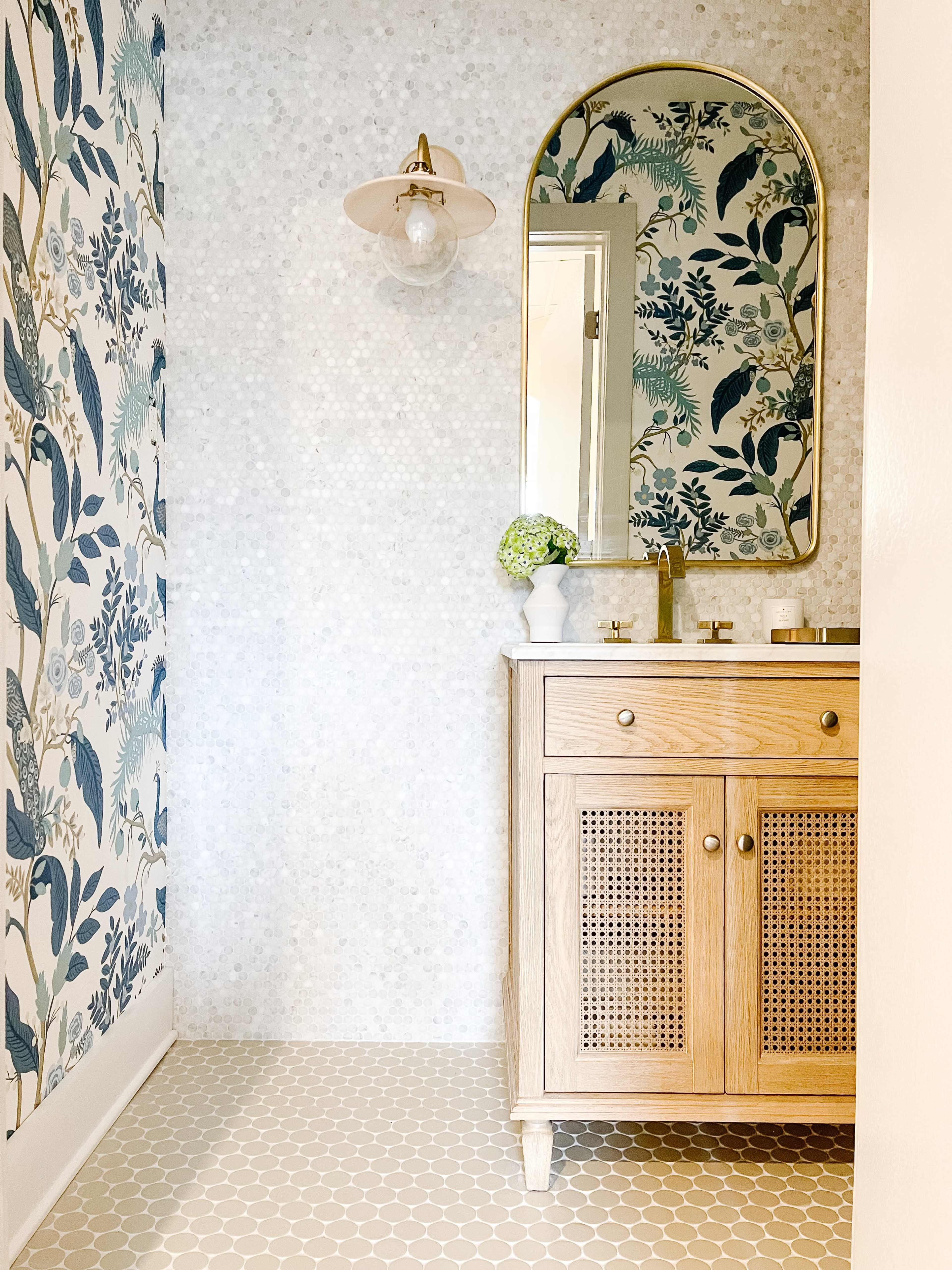A bathroom featuring a wooden vanity with a mirror, floral-patterned wallpaper, and a light fixture.