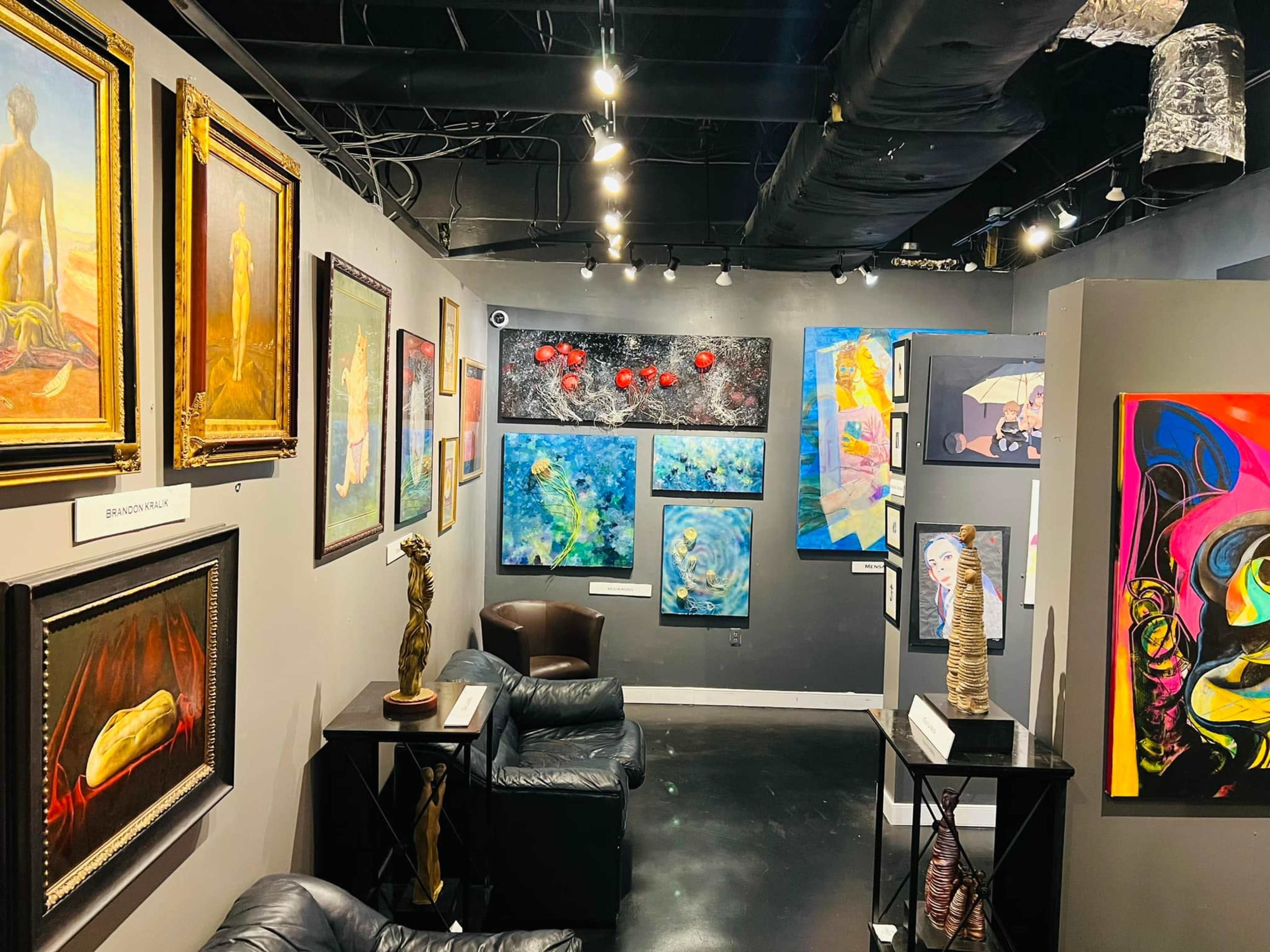 An art gallery featuring various paintings and sculptures displayed on the walls and furniture arranged in the space.