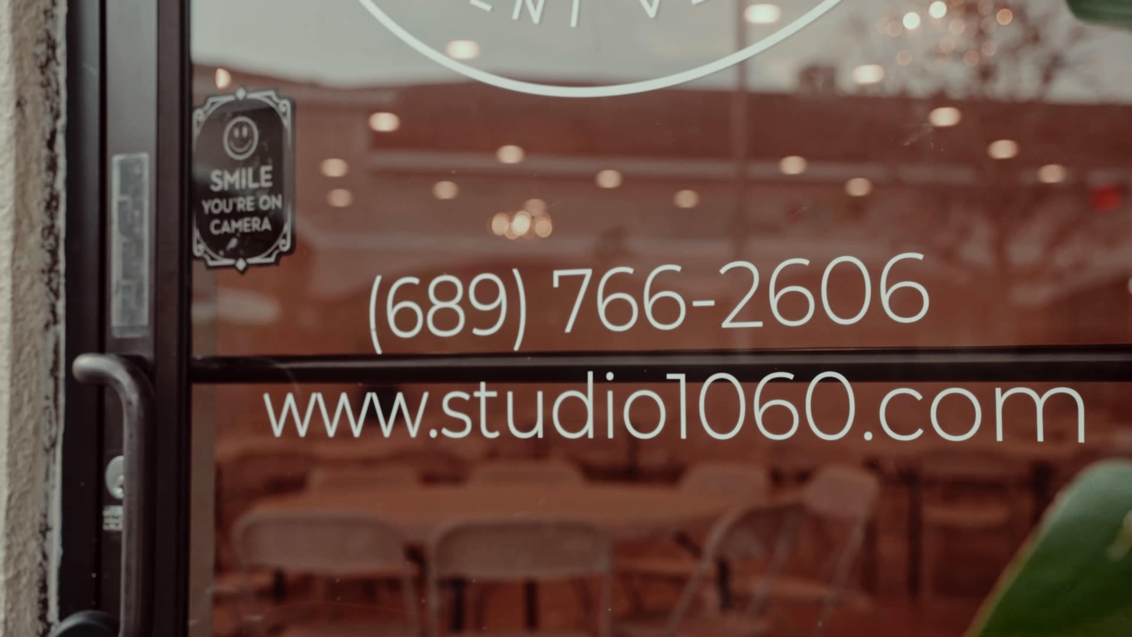A glass door with a sign displaying a phone number and website for a studio.