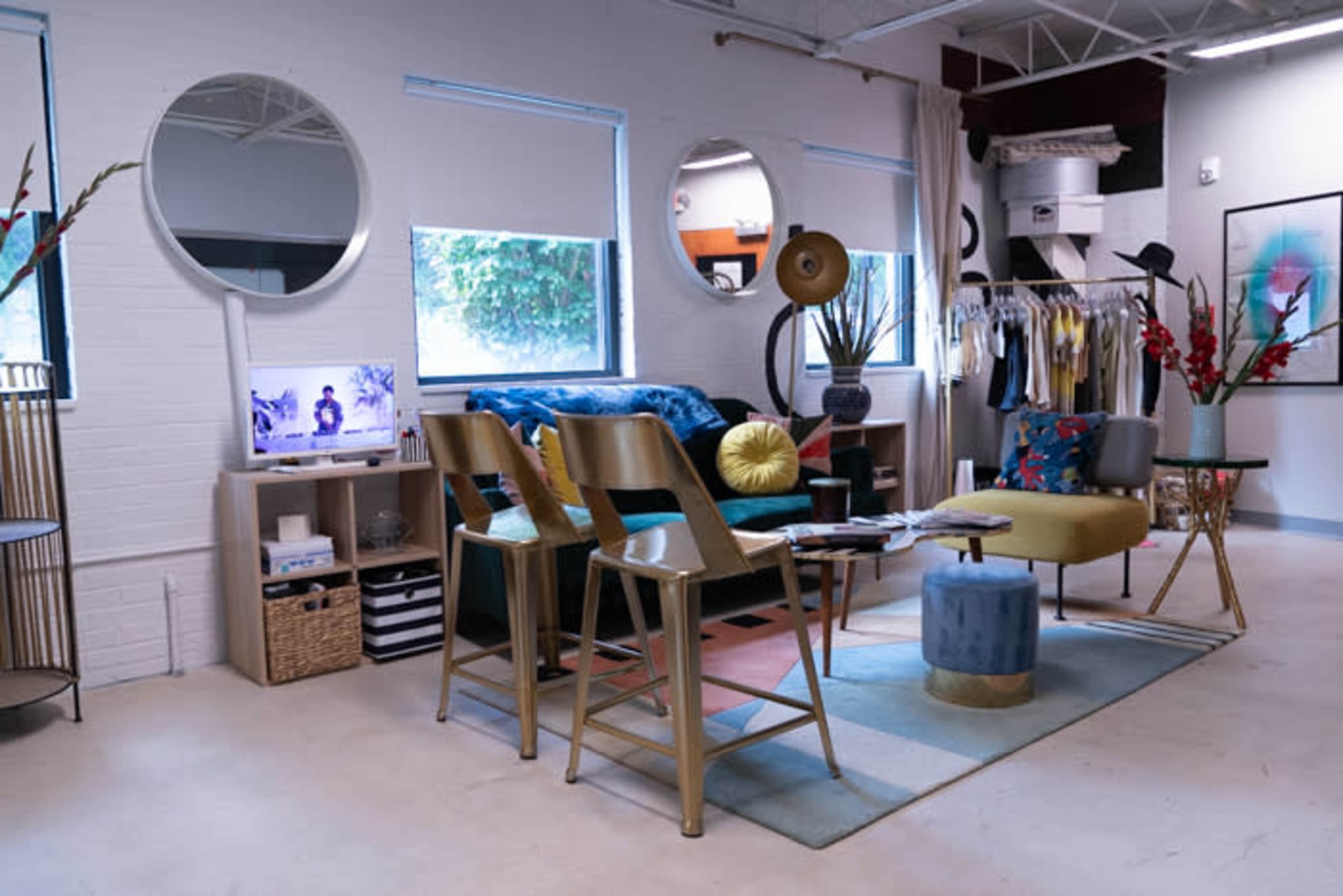 A modern living space featuring colorful furniture, decorative mirrors, and a television on a low cabinet.