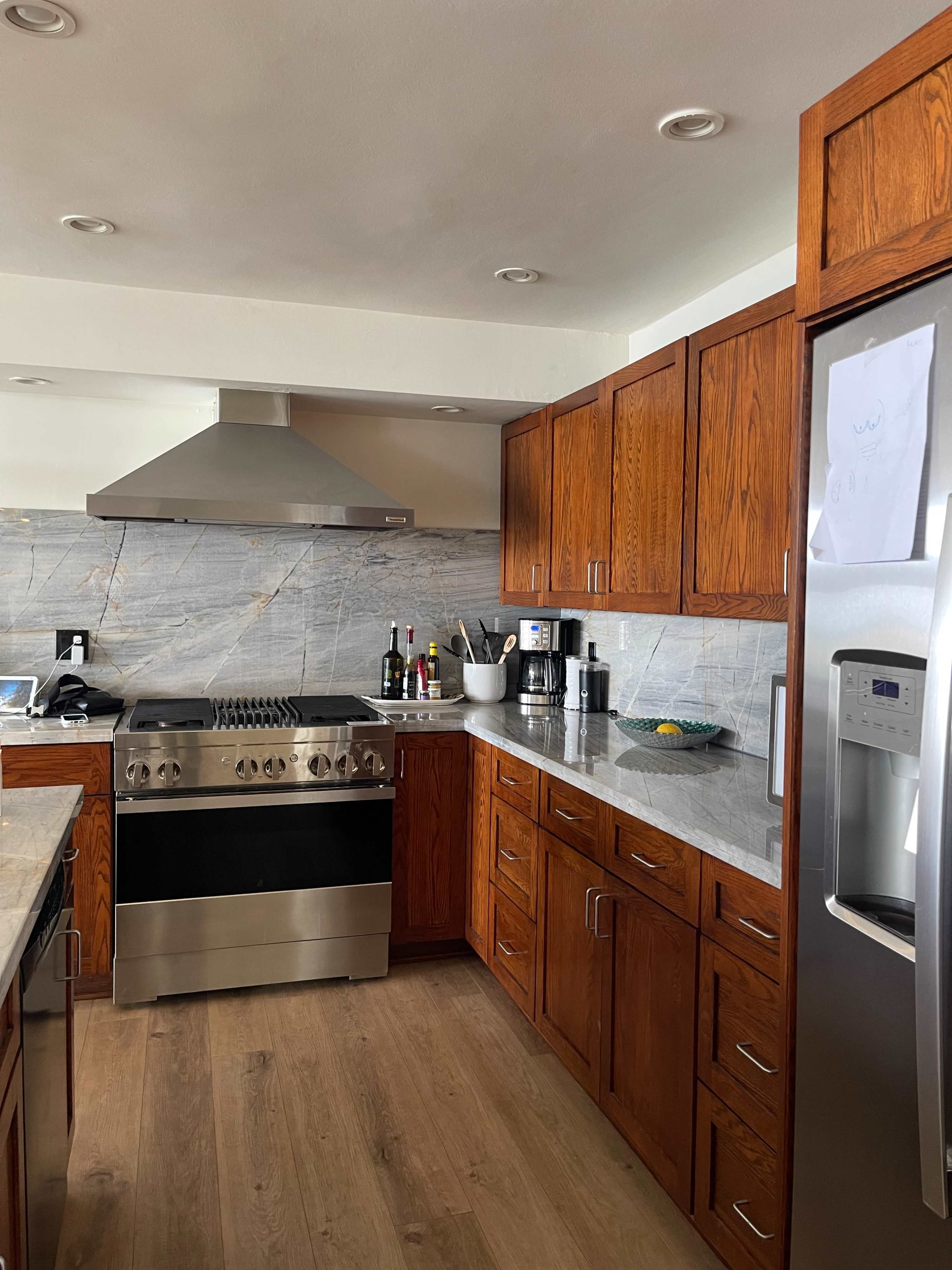 A modern kitchen with wooden cabinetry, a stainless steel stove, and a granite countertop.