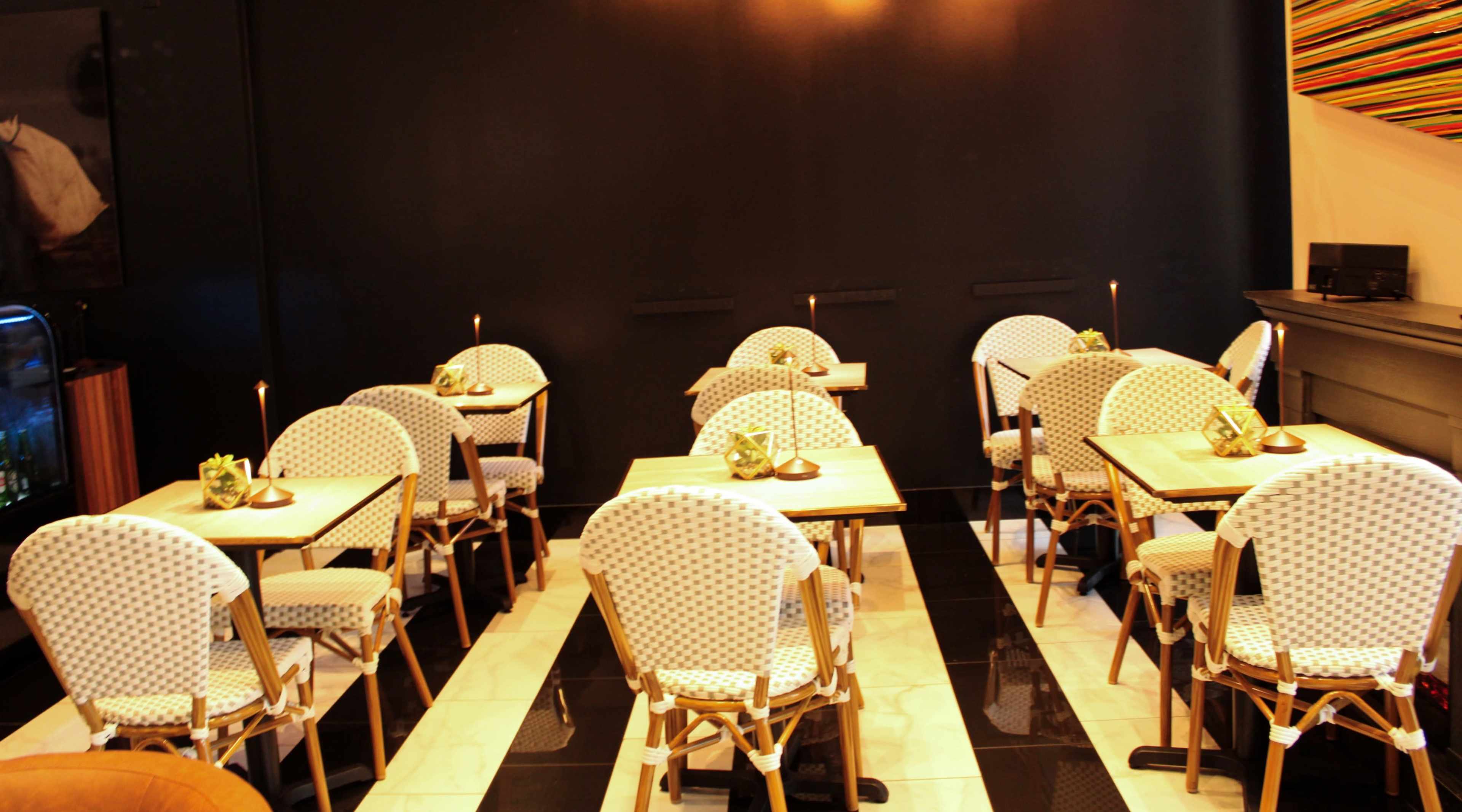 A cozy restaurant interior with several tables and patterned chairs arranged neatly on a tiled floor.