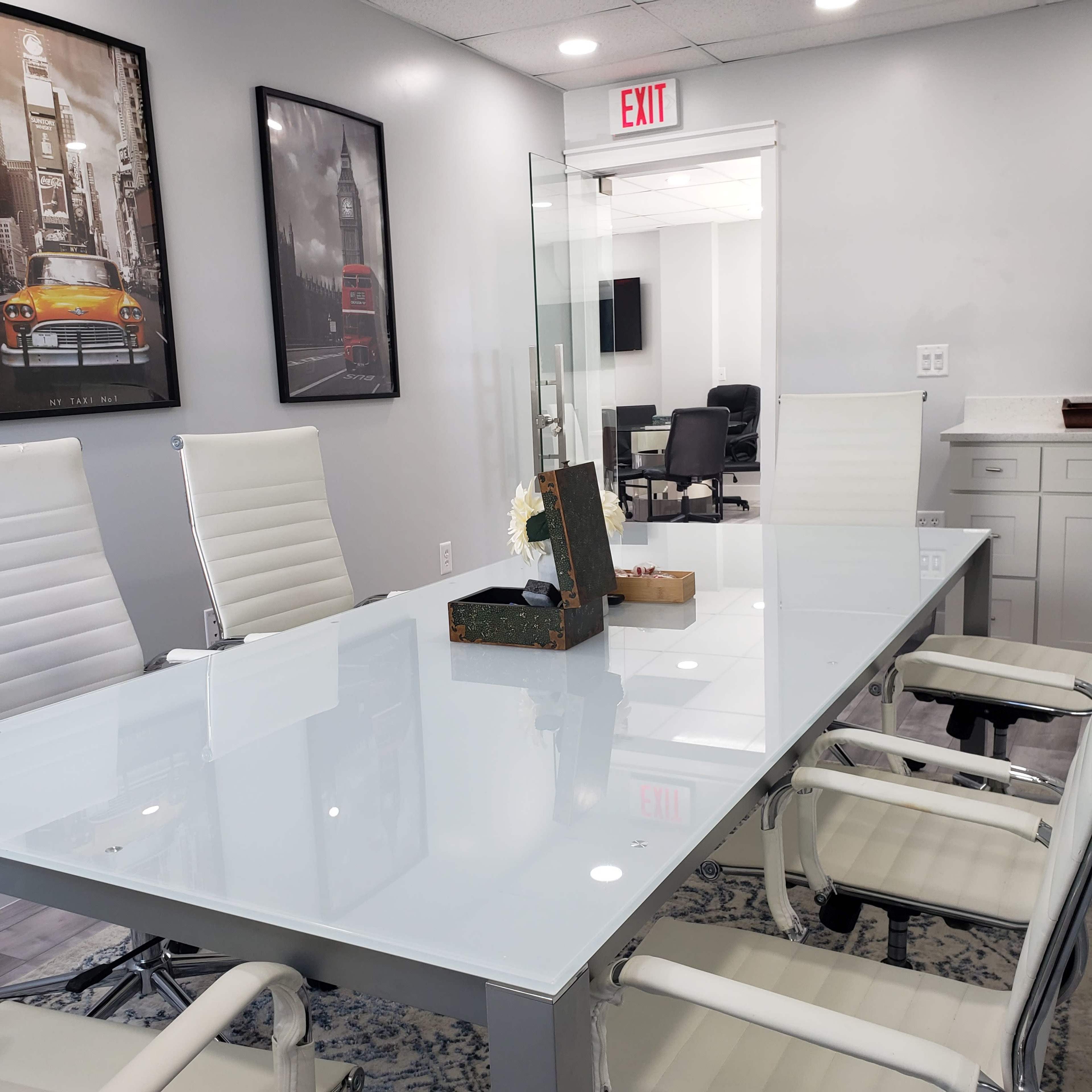 A modern conference room features a glass table, white chairs, and wall art depicting a cityscape.