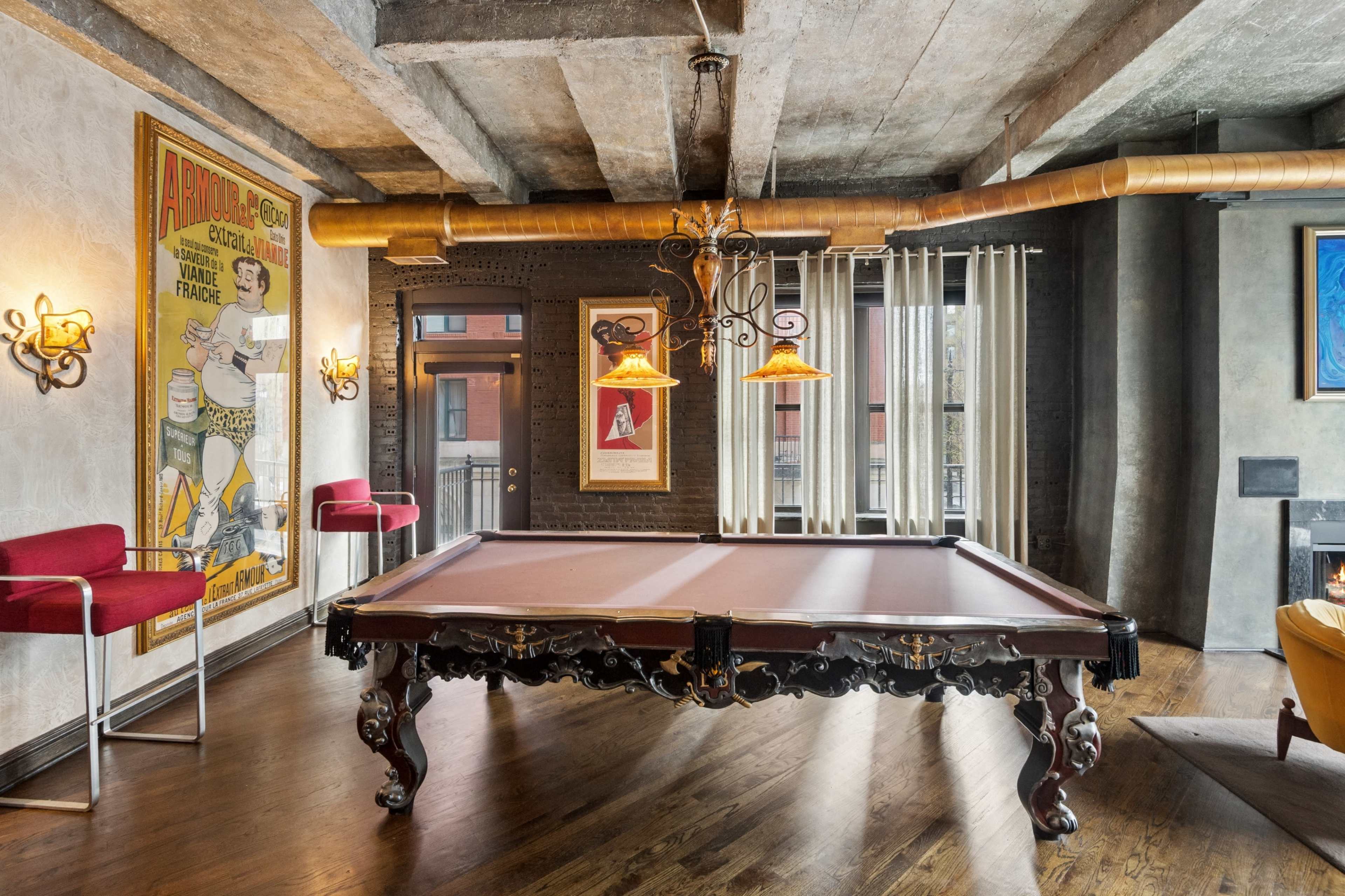 The image shows a stylish game room featuring a decorative billiards table, framed artwork on the walls, and modern lighting fixtures.