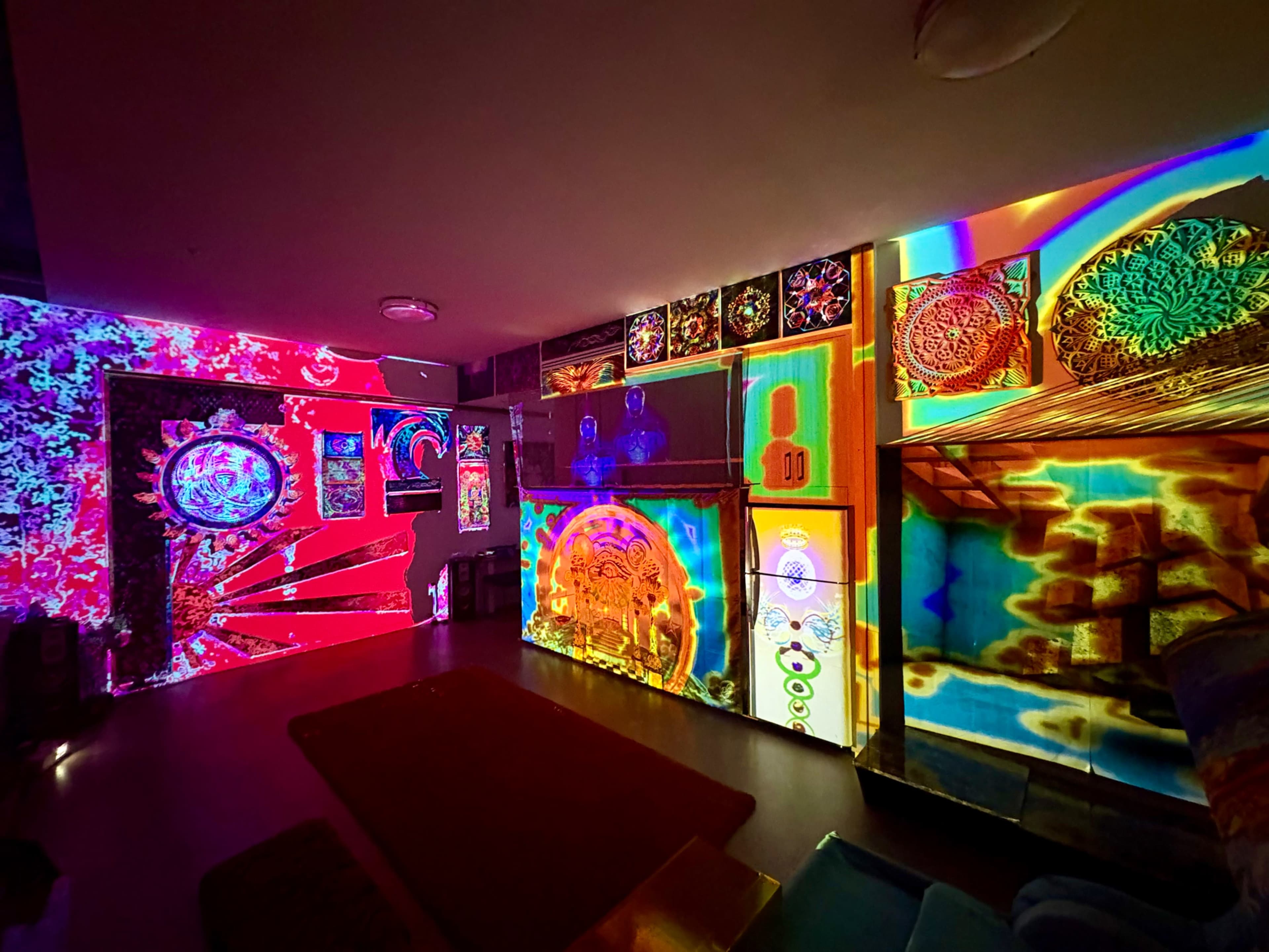 The room is filled with colorful light projections on the walls and furniture, creating a vibrant and dynamic atmosphere.