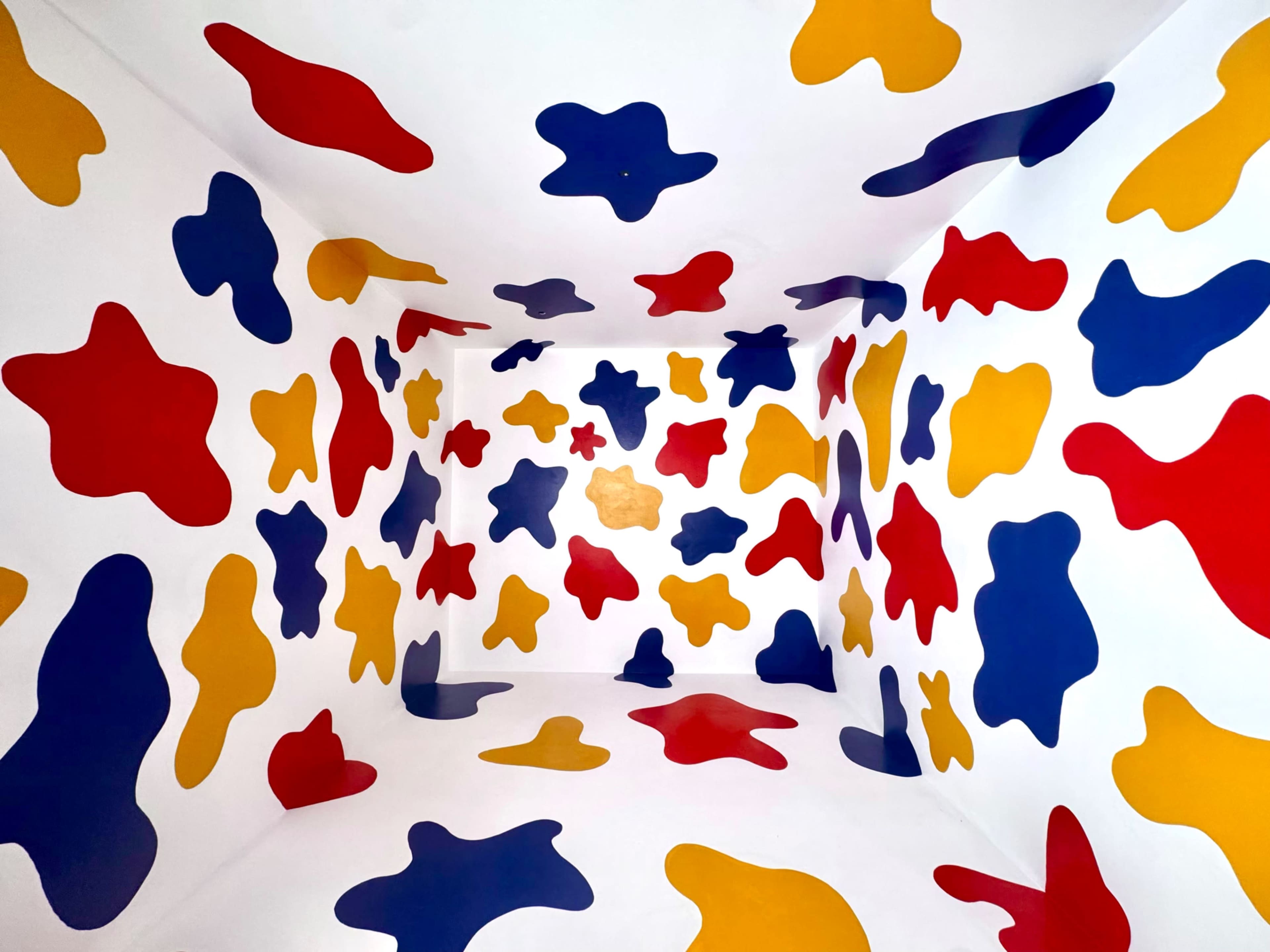 The room features walls decorated with abstract shapes in red, blue, yellow, and white, creating a vibrant, playful atmosphere.
