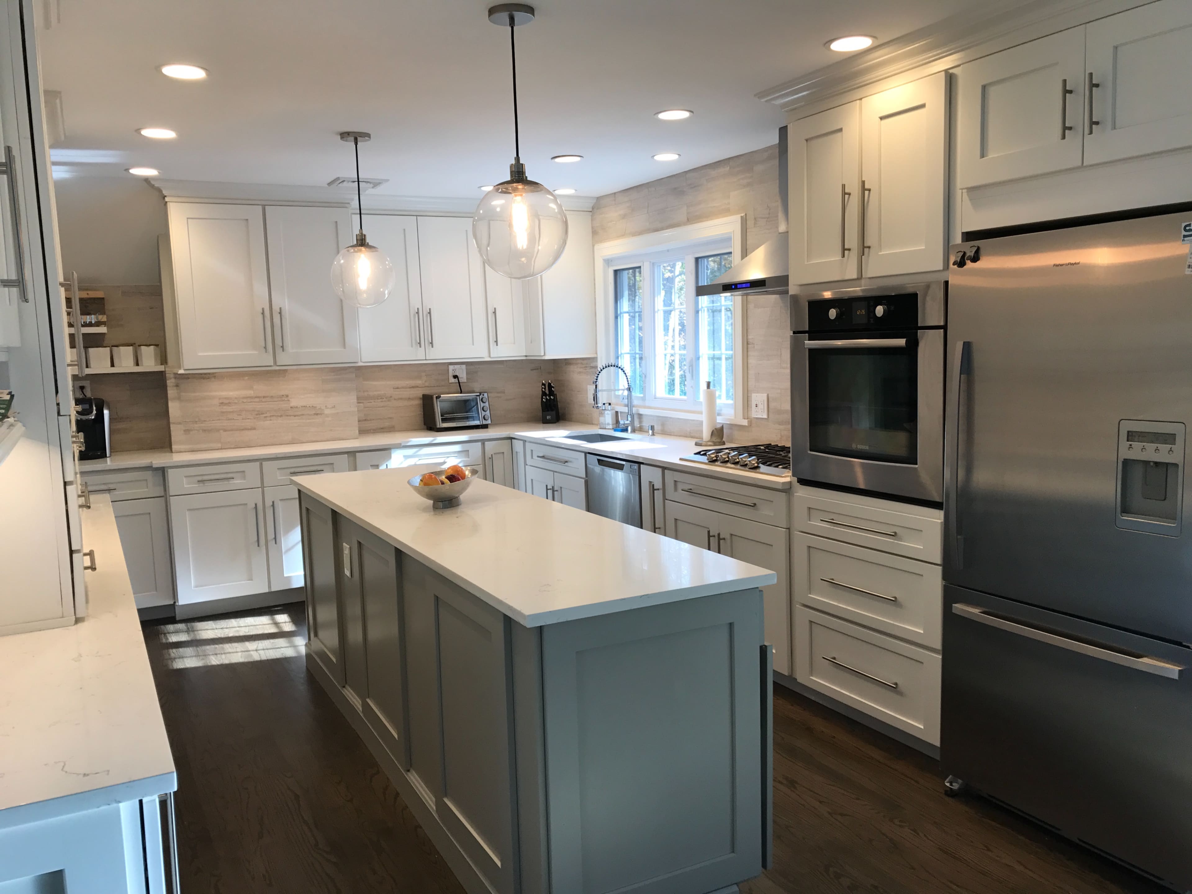A modern kitchen with white cabinetry, stainless steel appliances, and a central island with a countertop.