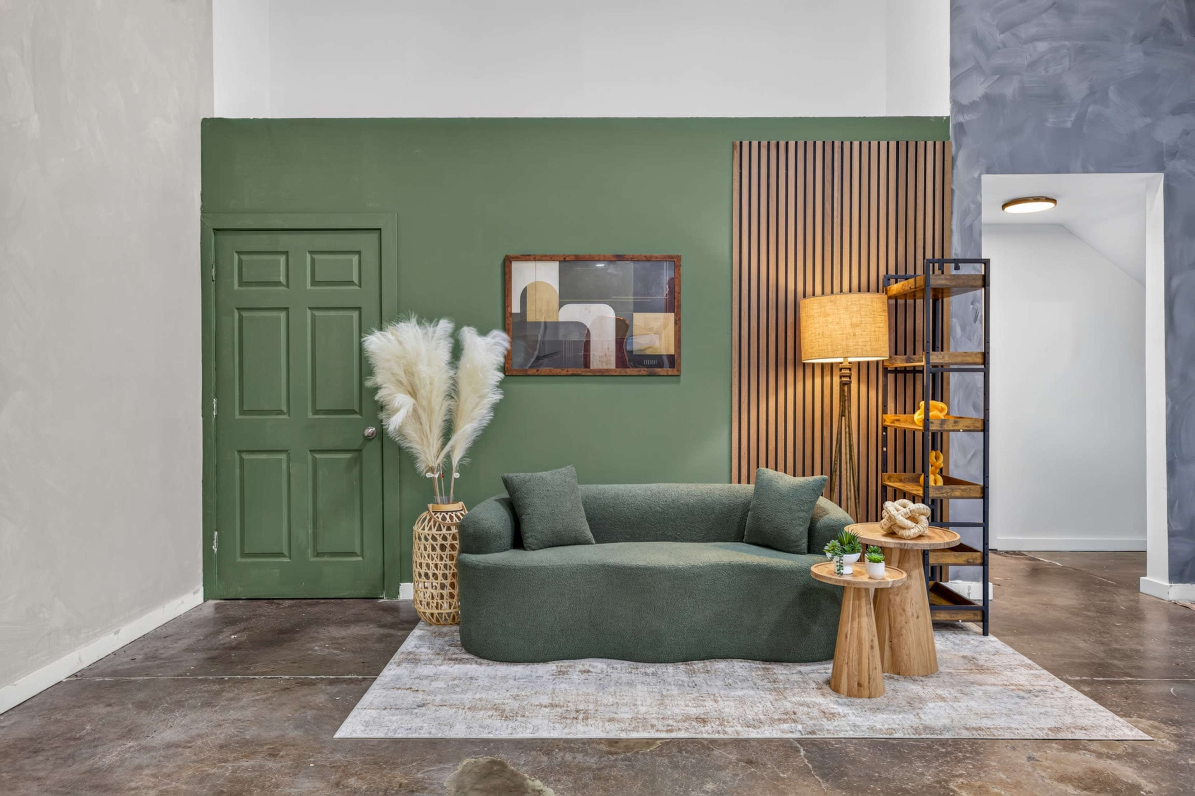 The image features a modern interior space with a green accent wall, a curved sofa, a wooden table, and decorative elements like a potted plant and a floor lamp.