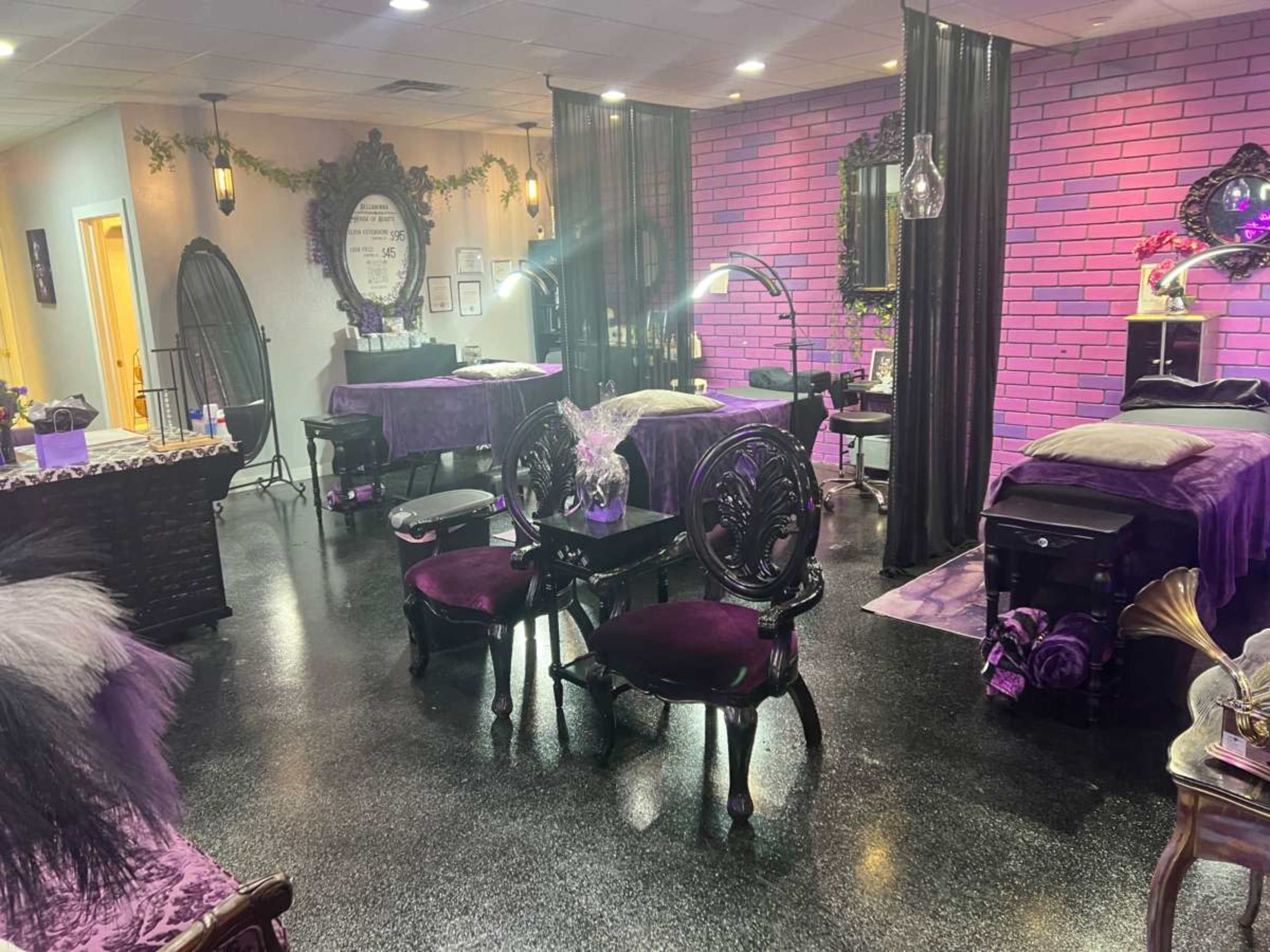 The image shows a tattoo studio with purple decor, featuring several tattoo stations separated by black curtains and vintage-style seating.