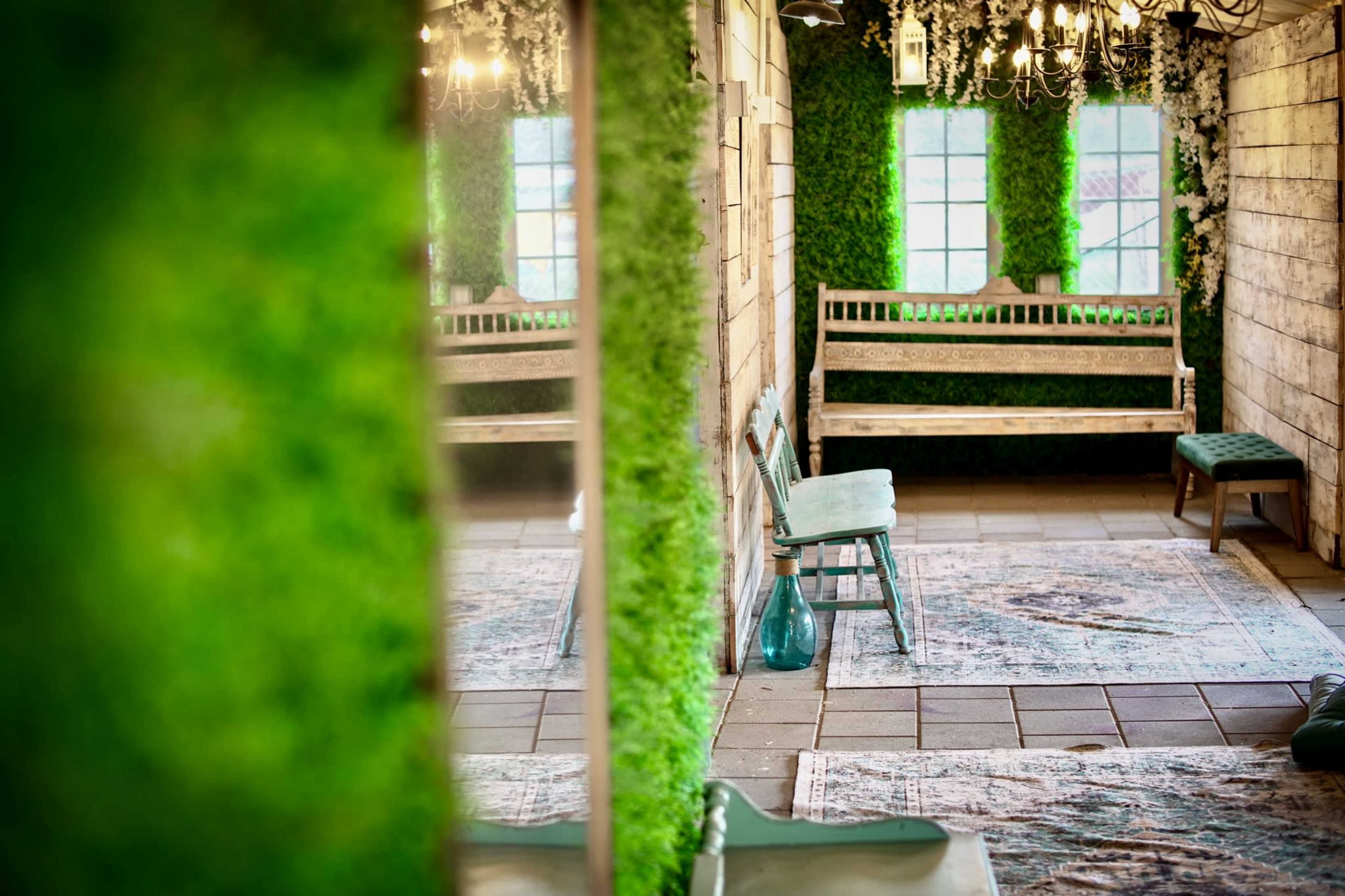 A room with wooden walls, green moss-covered sections, a wooden bench, and a vase placed on the floor.