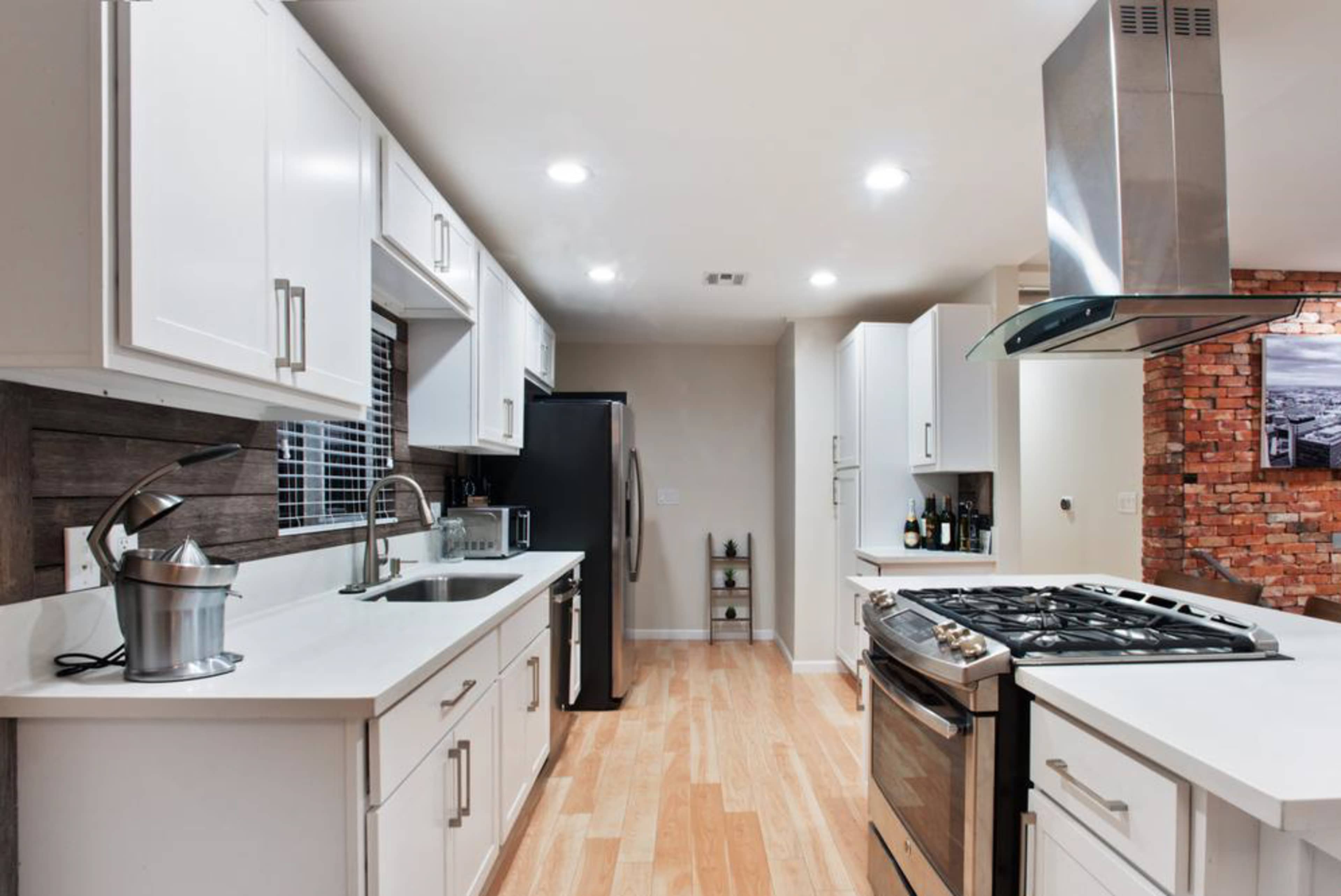 A modern kitchen with white cabinetry, a stainless steel stove, and hardwood flooring.