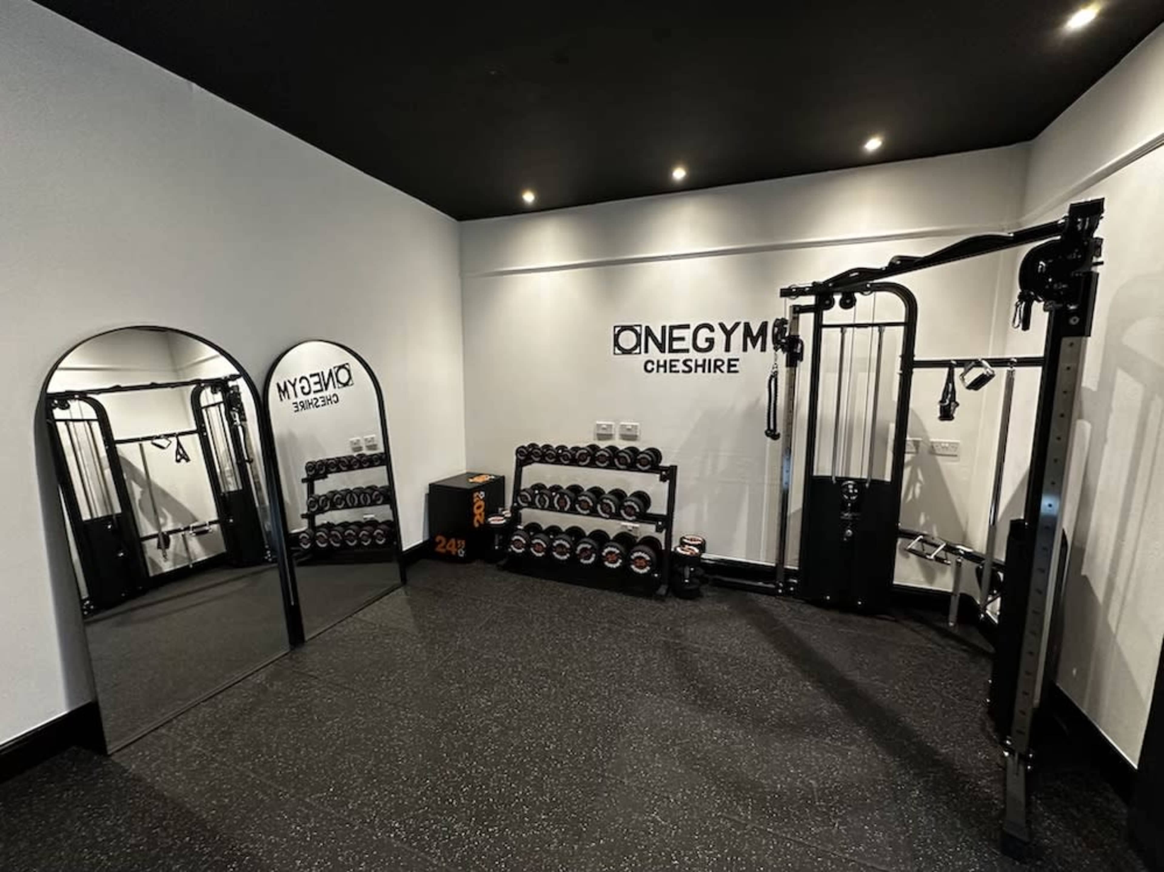 A small gym space featuring exercise equipment, a mirror, and a rack of dumbbells against the wall.