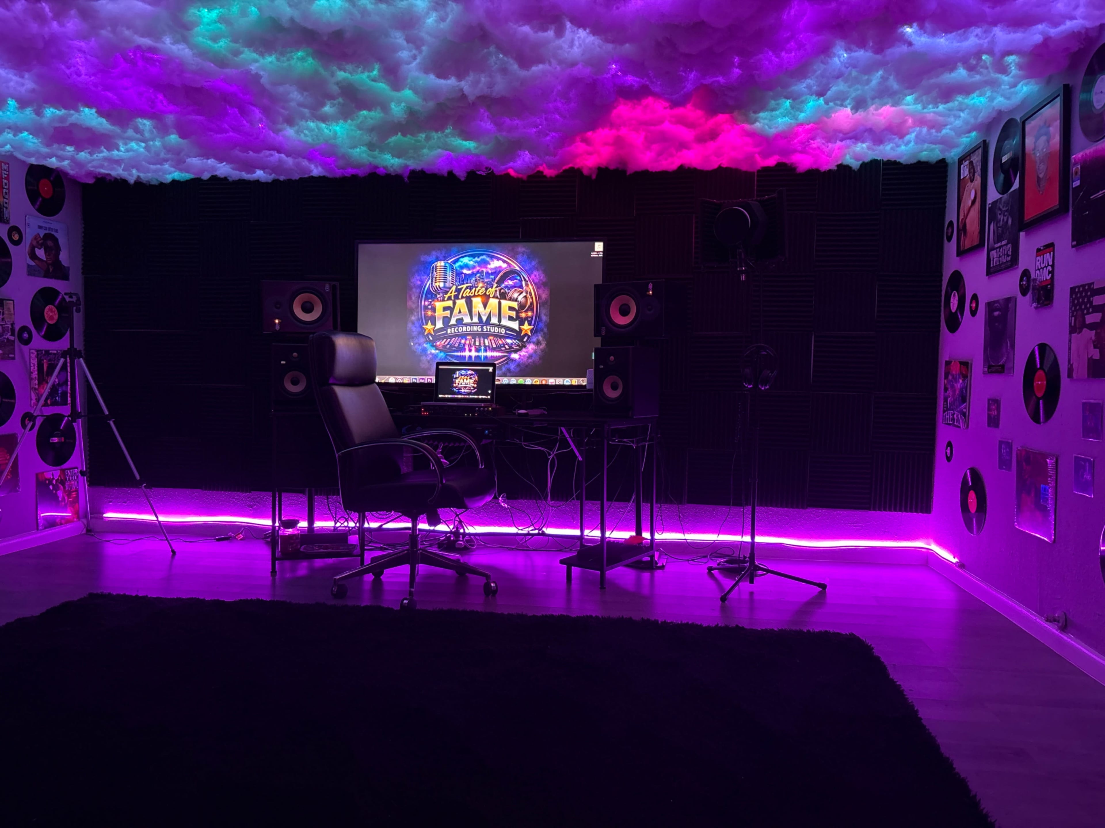 The image shows a music recording studio with colorful cloud-like ceiling decorations, a desktop computer displaying a "FAME" graphic, and audio equipment.