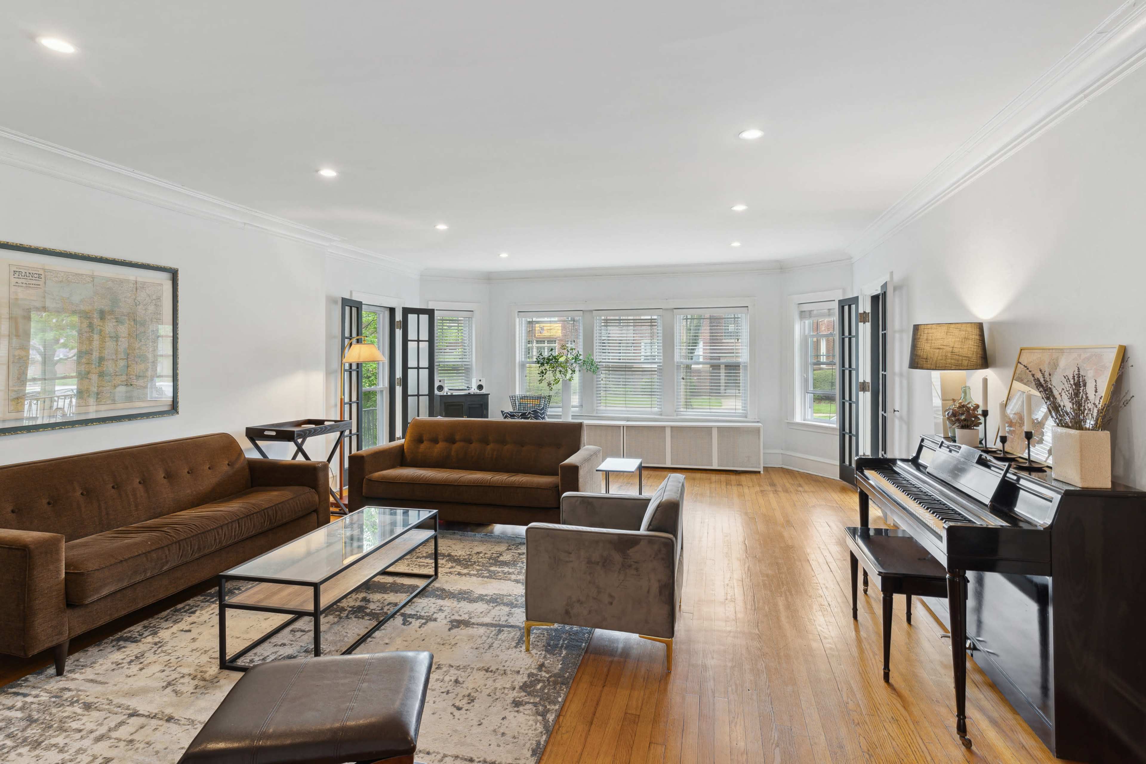 The room features a spacious living area with a mix of seating, a coffee table, and a piano.