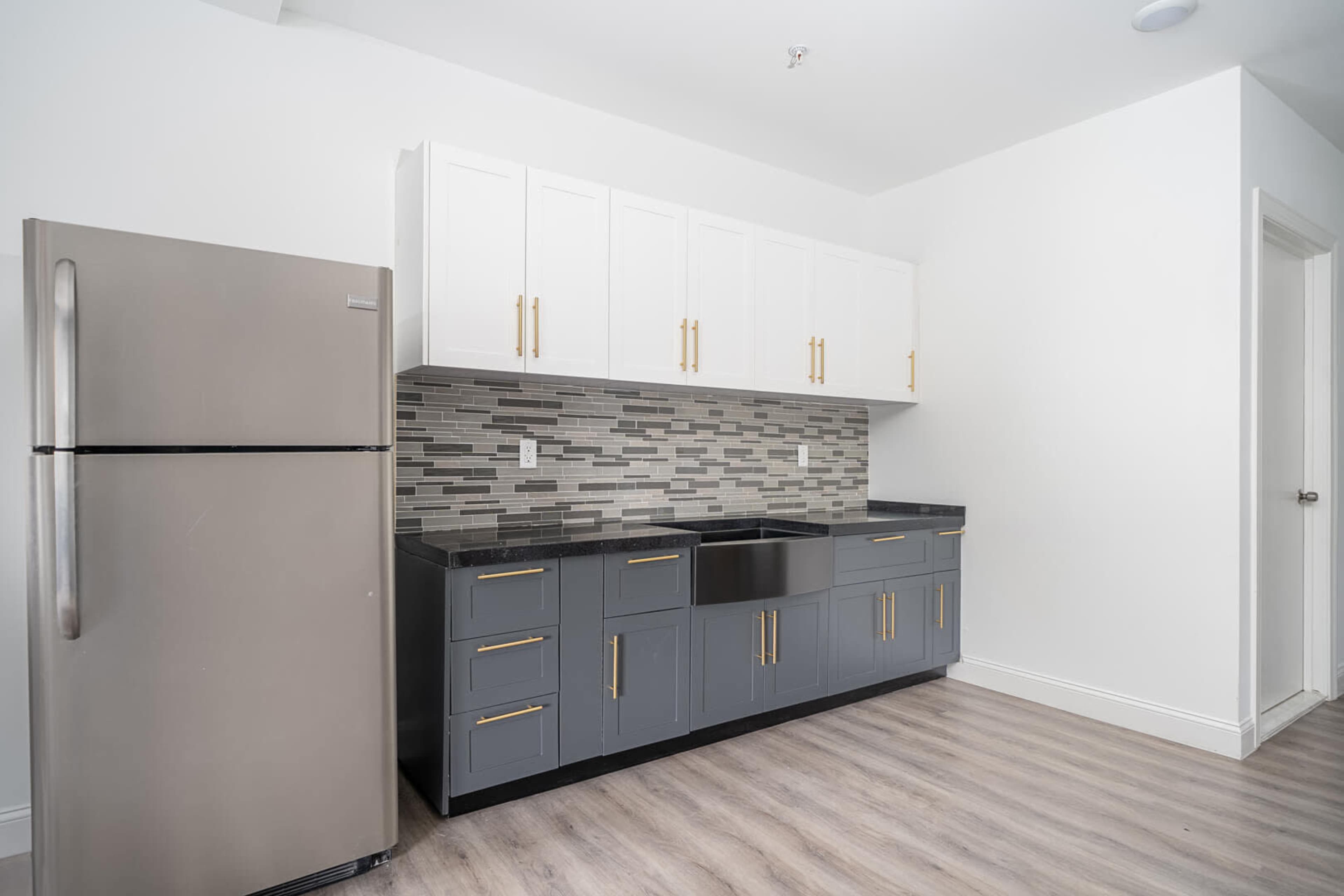 A modern kitchen layout with stainless steel appliances, gray cabinetry, and a tiled backsplash.