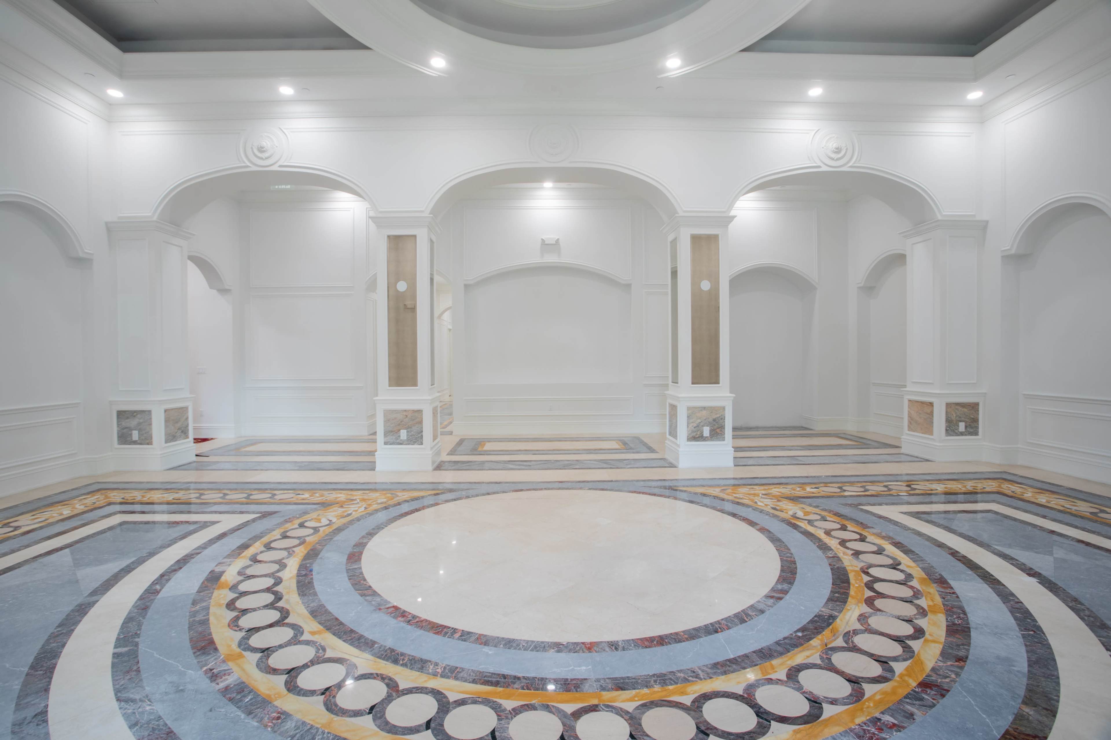 A spacious, elegantly designed room with a circular marble floor pattern and arched architectural elements.