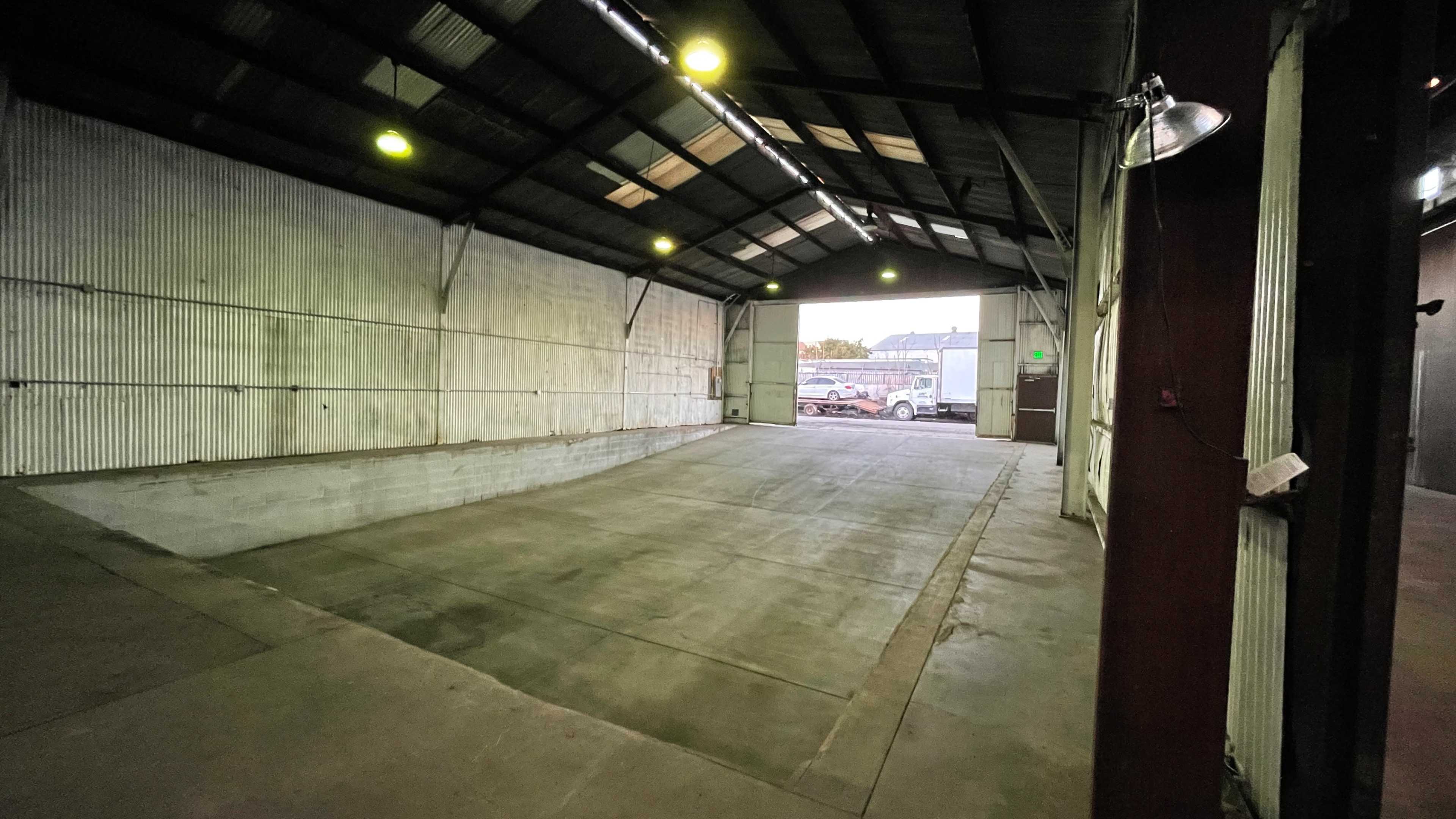 A large, empty indoor warehouse space with concrete flooring and metal walls.